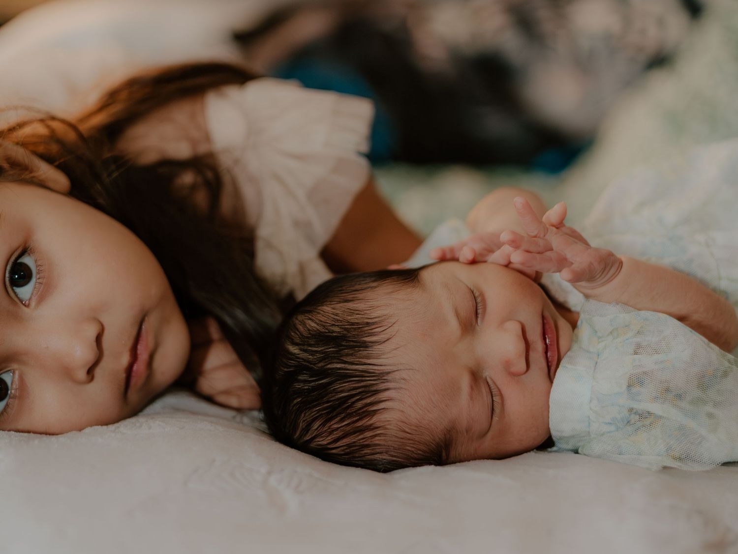 Sleeping baby rests peacefully on soft floral bedding in natural light.