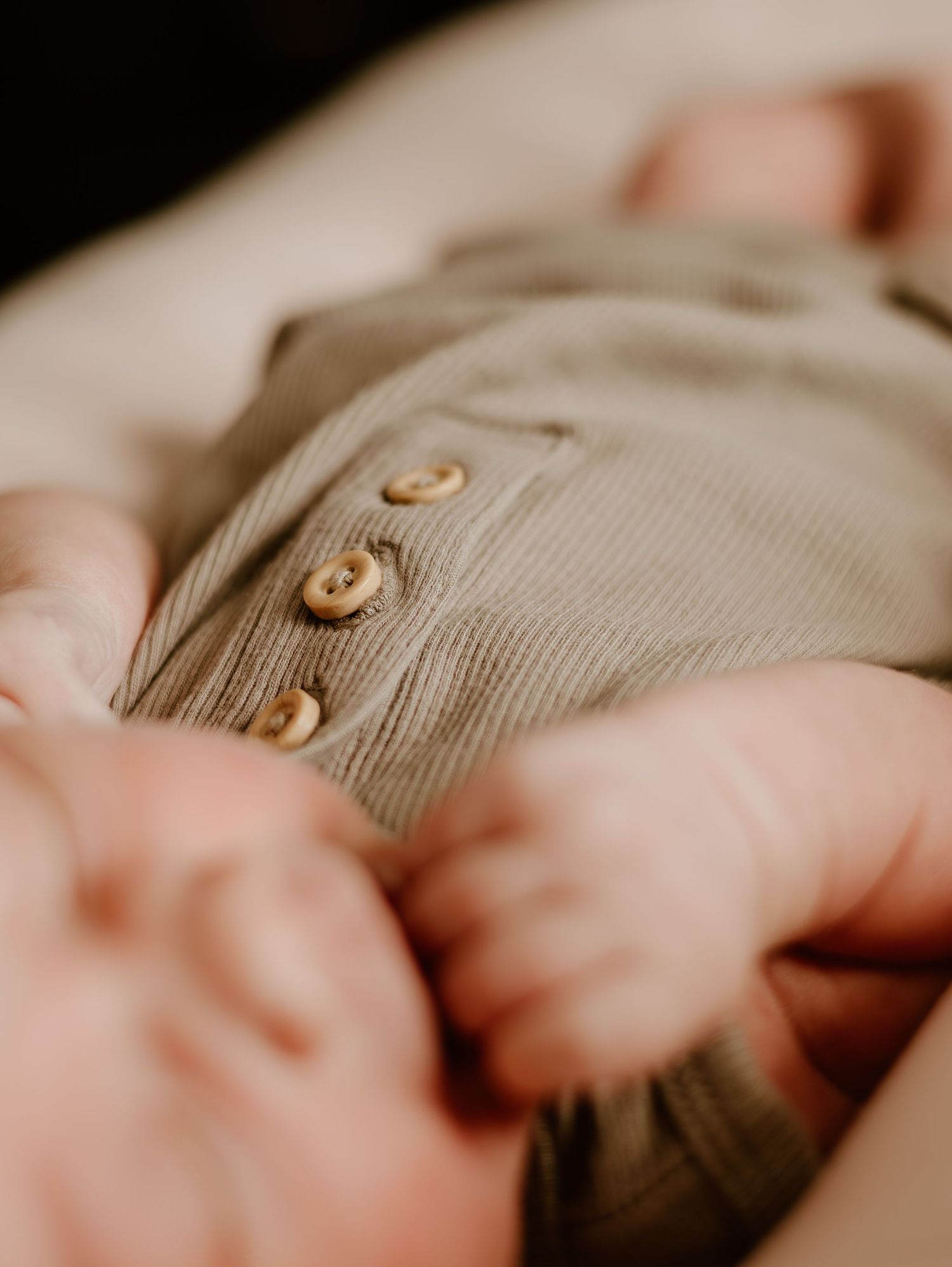 Close-up detail of brown knit fabric with decorative buttons in soft lighting.