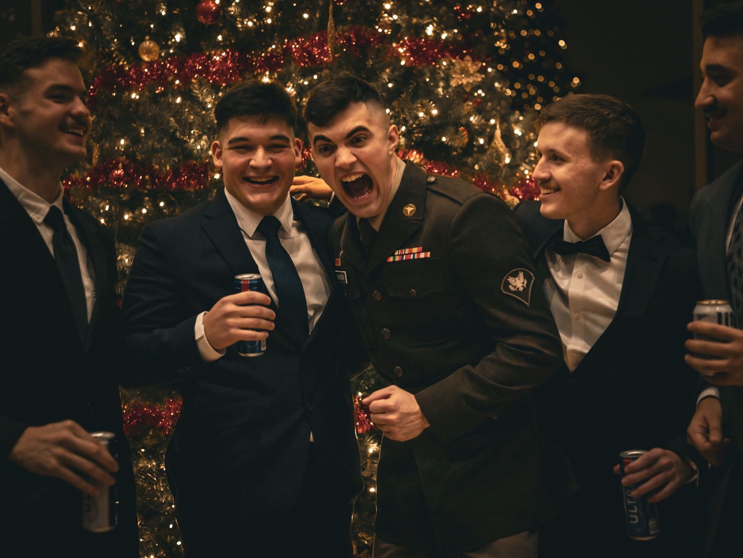 A group in formal attire celebrating near a decorated Christmas tree.