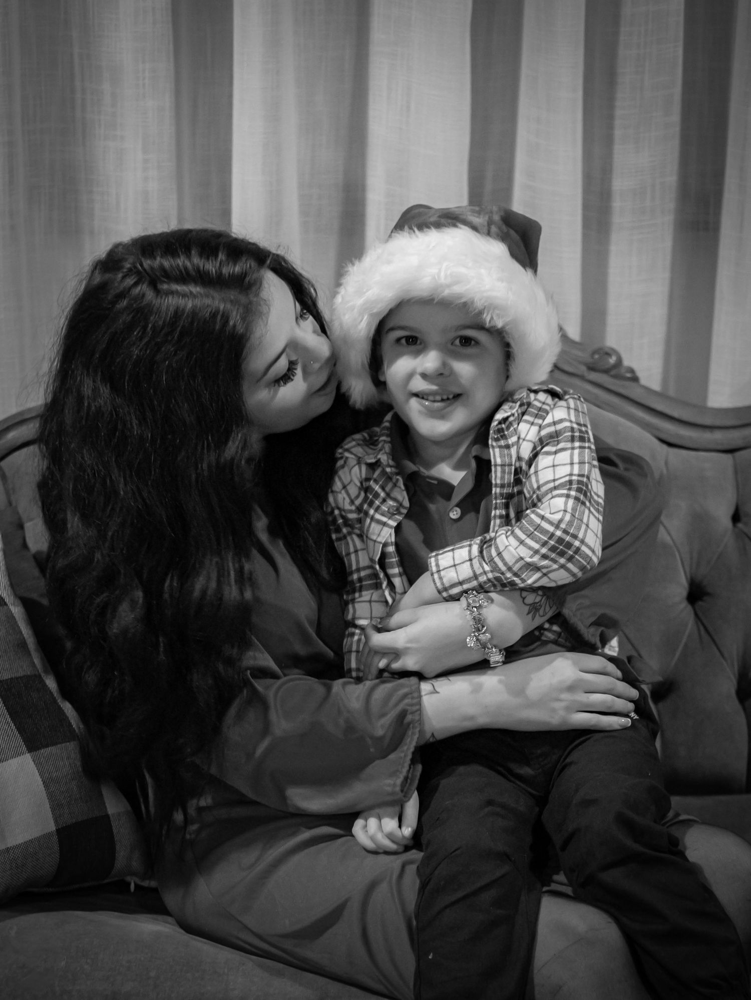 Intimate black and white portrait of mother and child in Santa hat sharing tender moment.