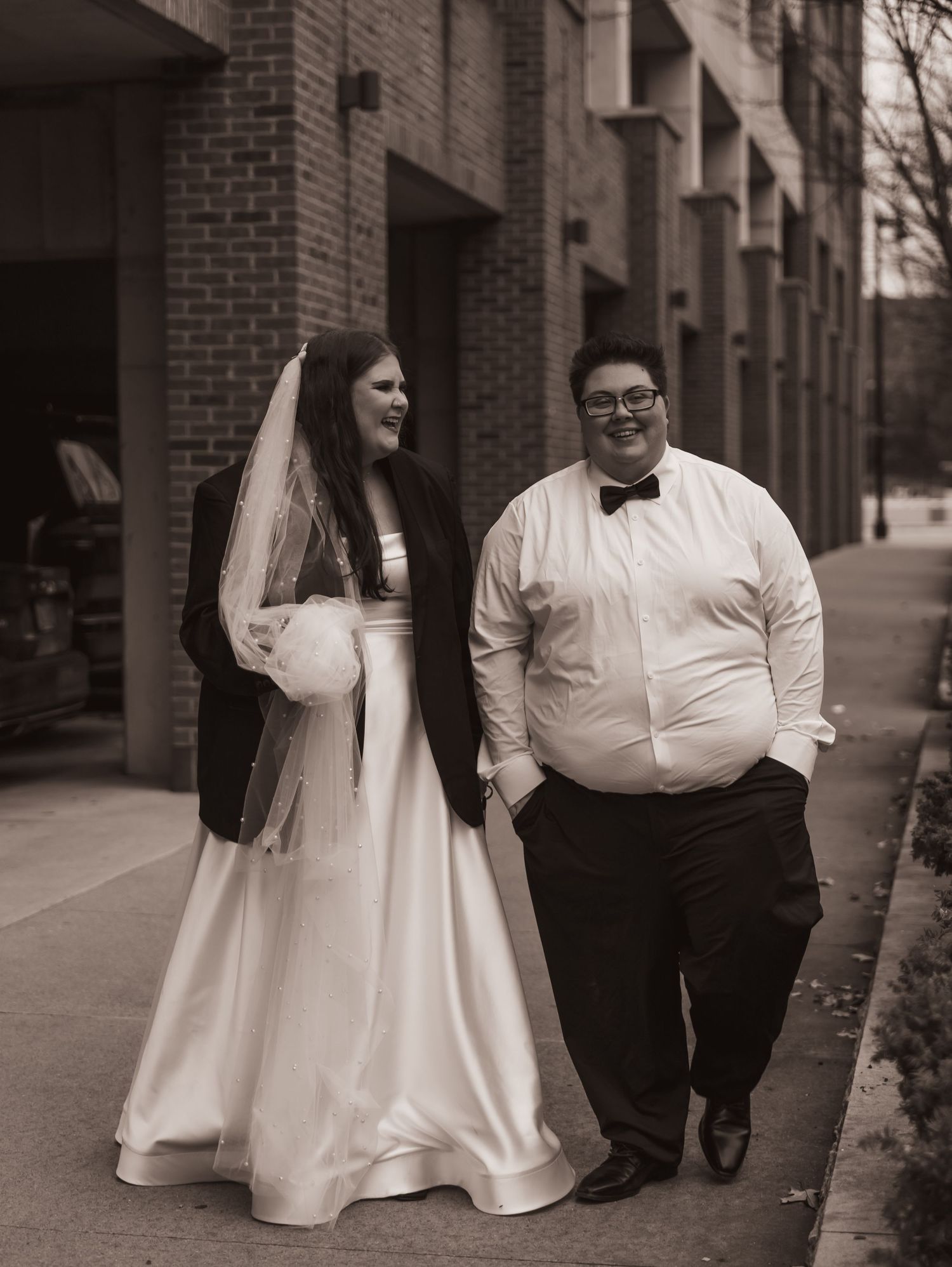 A series of black and white photos showing a newlywed couple walking and embracing against an industrial brick backdrop.