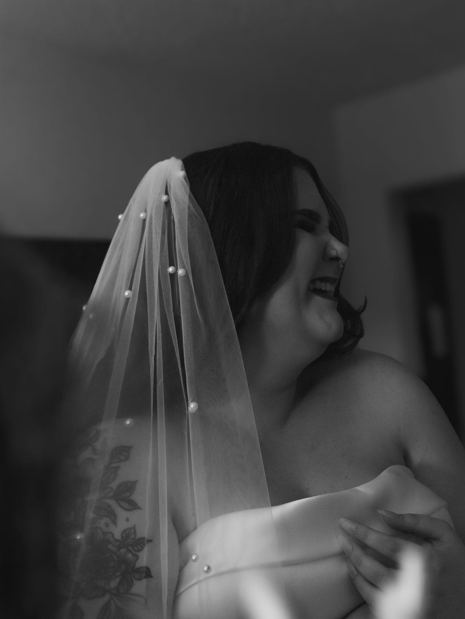 Close-up detail of a delicate white wedding veil silhouetted against a dark background.