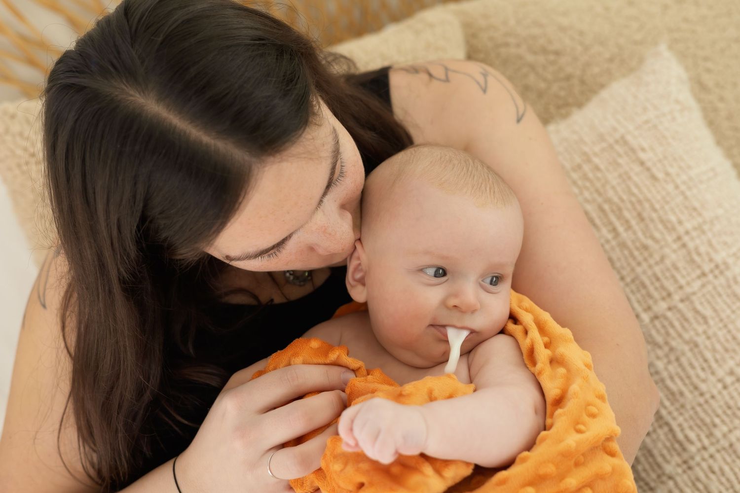A tender moment between parent and baby during playtime on a soft beige blanket.