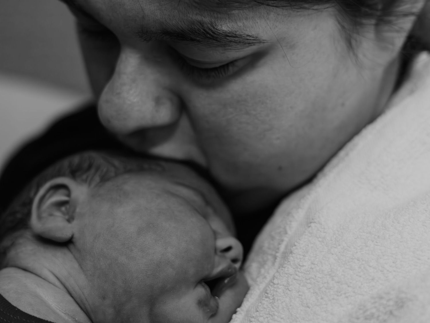 A series of black and white photographs showing tender moments between parent and baby in close-up shots.
