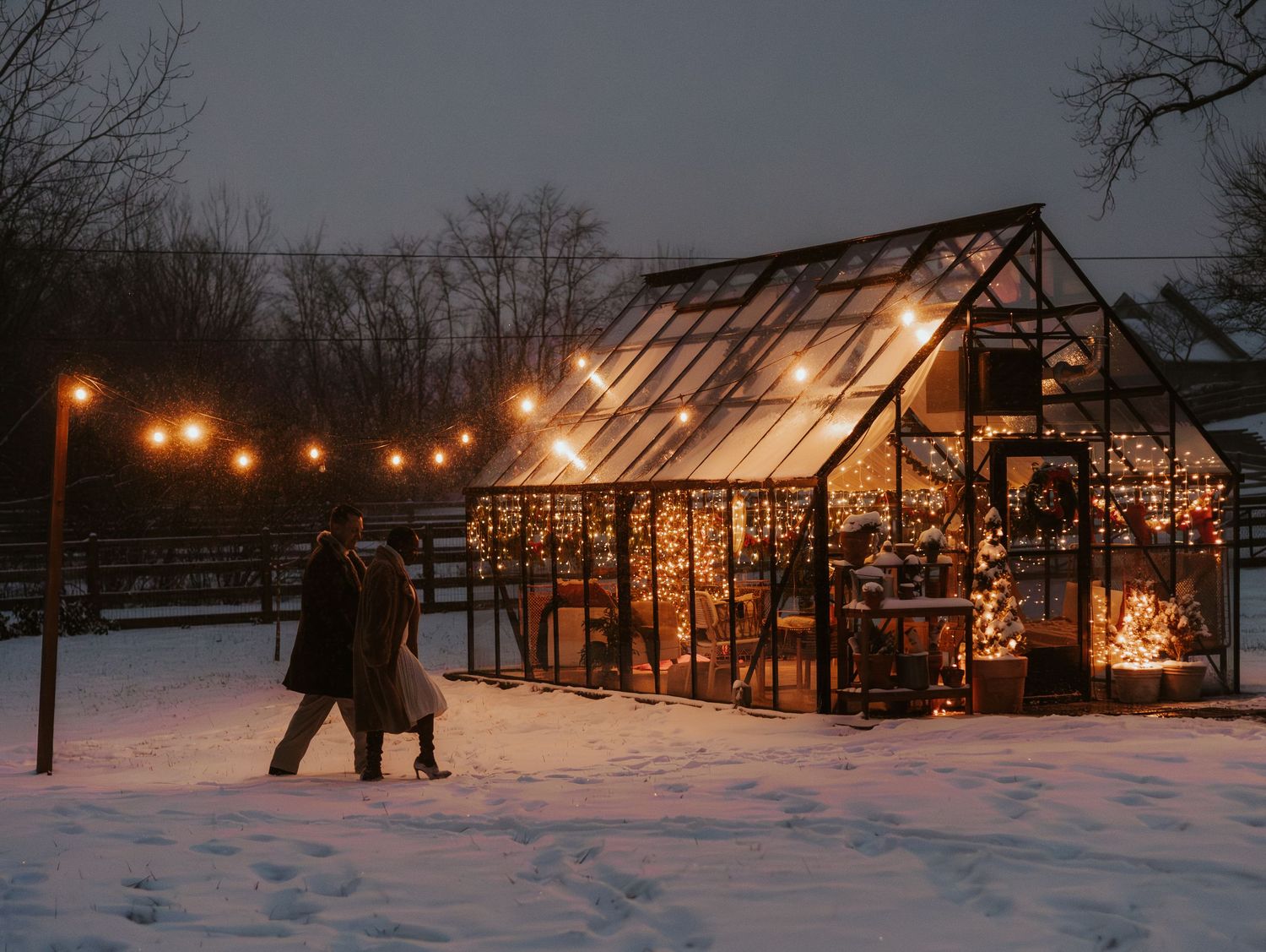 Silhouetted wooden structures glow warmly against a snowy winter landscape at dusk.