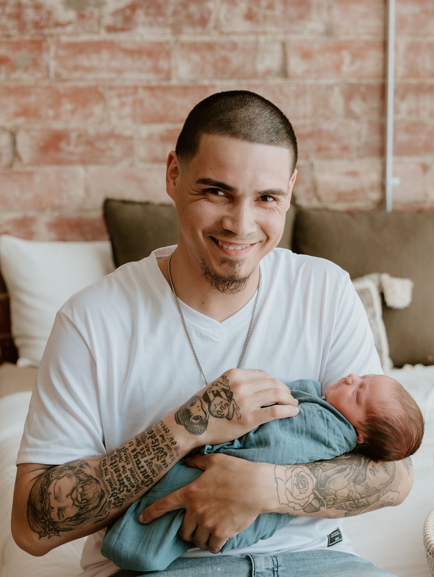 Intimate series of a parent with tattoos holding and gazing lovingly at their newborn baby.