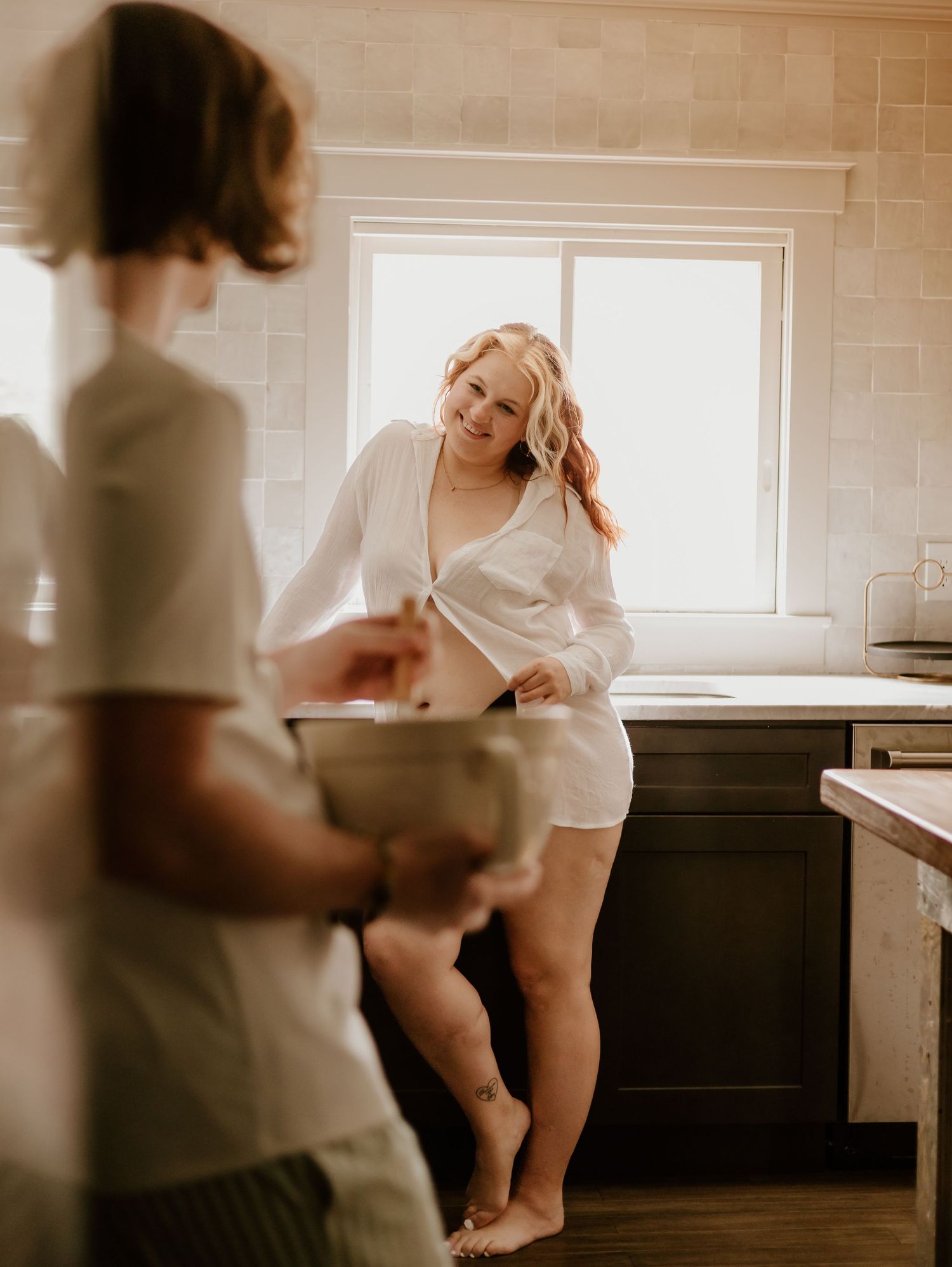 Romantic lifestyle photography featuring white clothing and natural lighting in a modern kitchen setting.