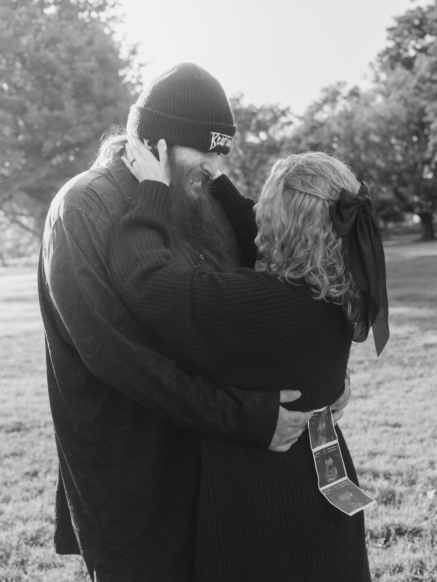 A couple embraces while looking at photographs together in a scenic outdoor setting.