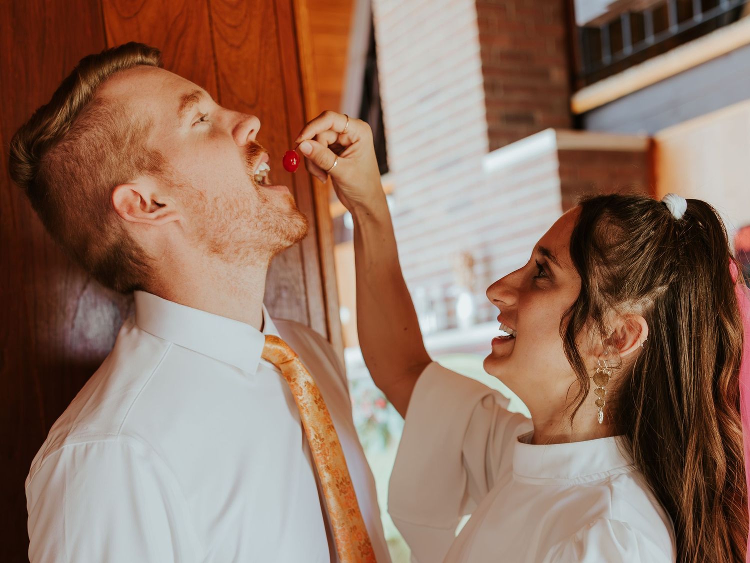 Romantic candid moments captured in warm tones against wooden and brick backgrounds.