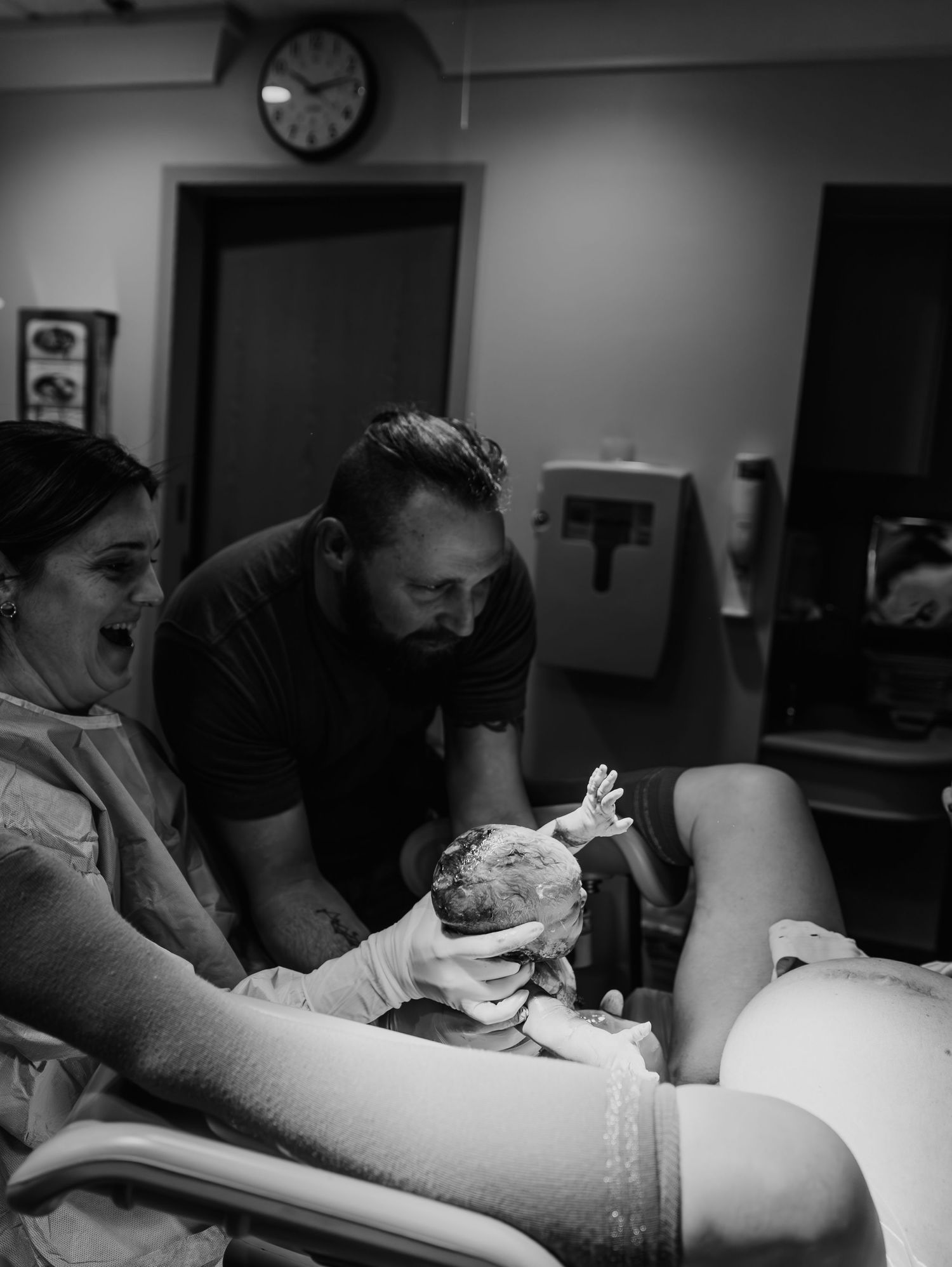 Black and white photo capturing the emotional moment of birth in a hospital delivery room.