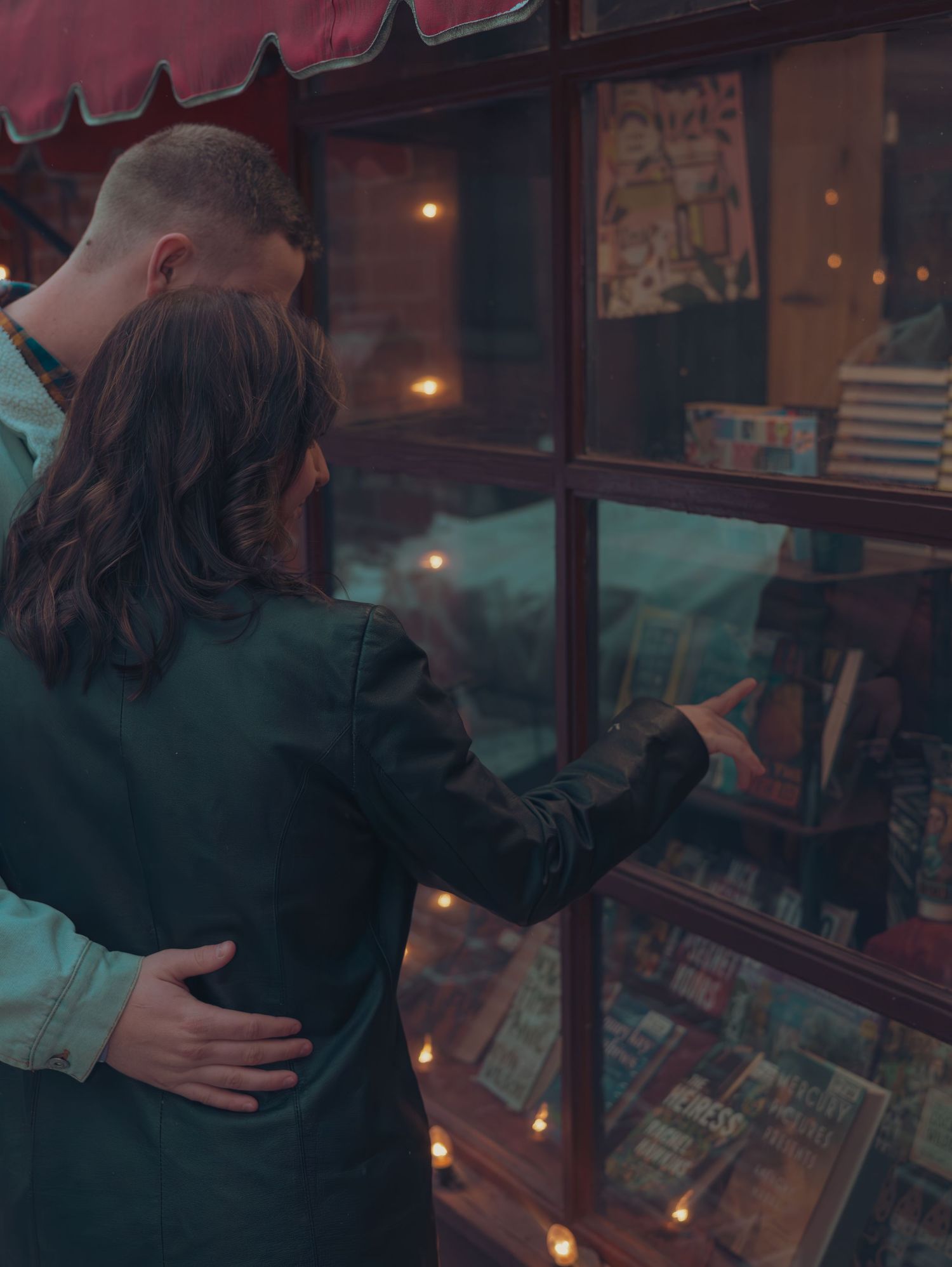 A romantic moment unfolds in a dimly lit bookstore with warm candlelight creating an intimate atmosphere.