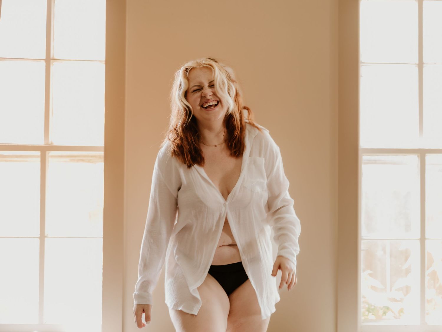 Intimate lifestyle photography session with couple in white button-down shirts by sunlit windows.