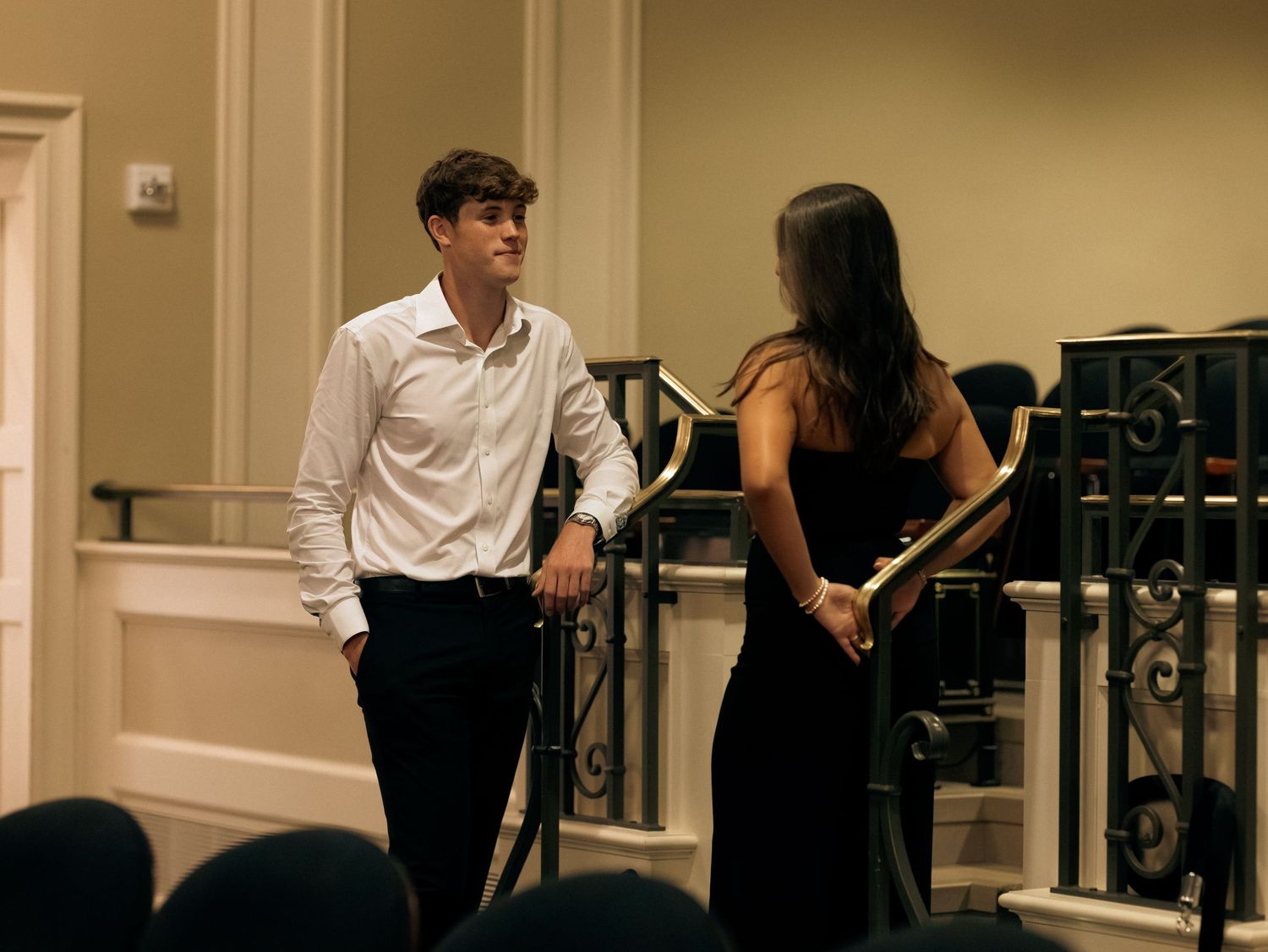 A couple shares a playful moment near decorative railings indoors.