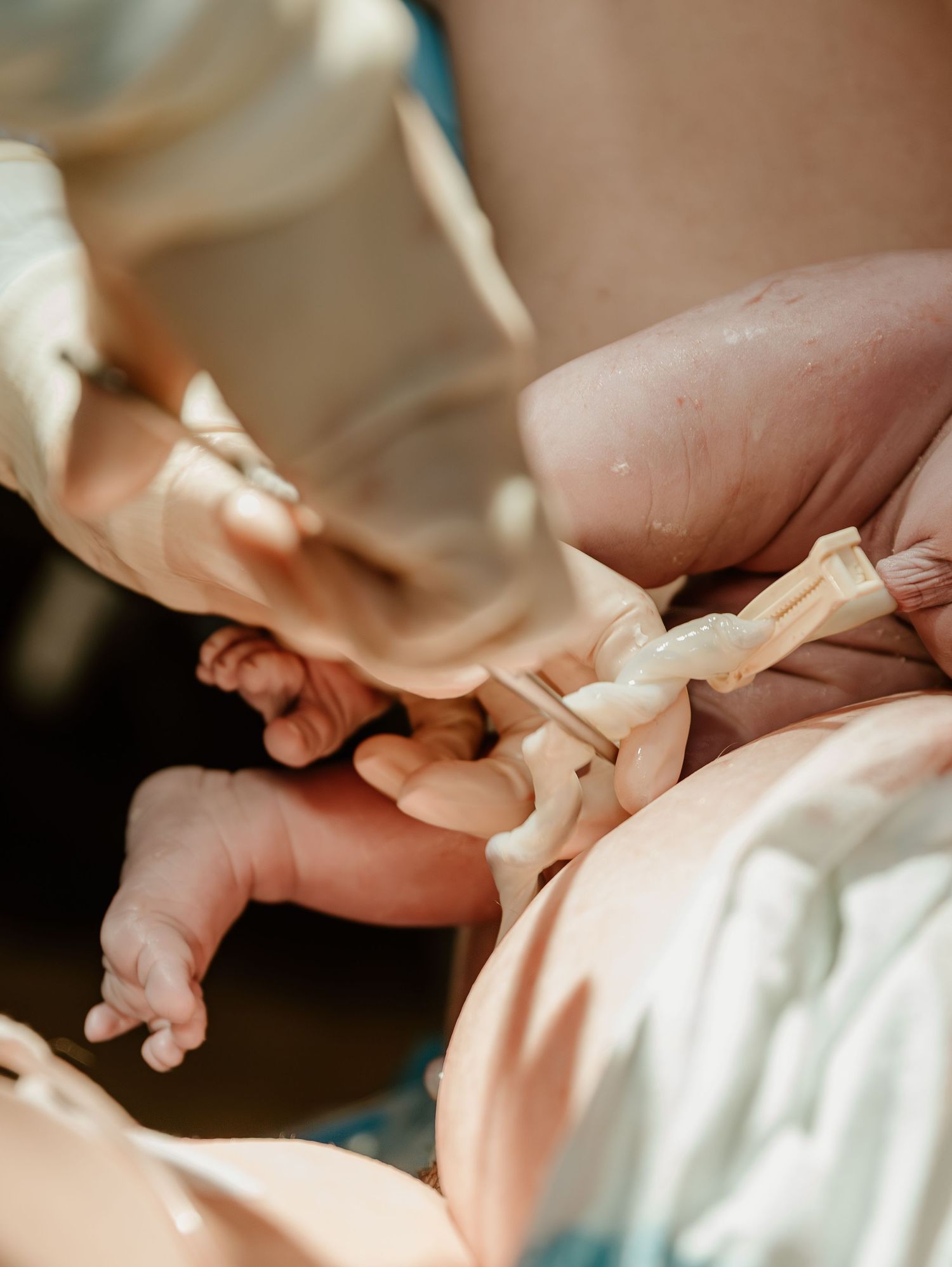 A close-up shot of tiny feet in soft focus while someone ties a delicate cream ribbon around them.