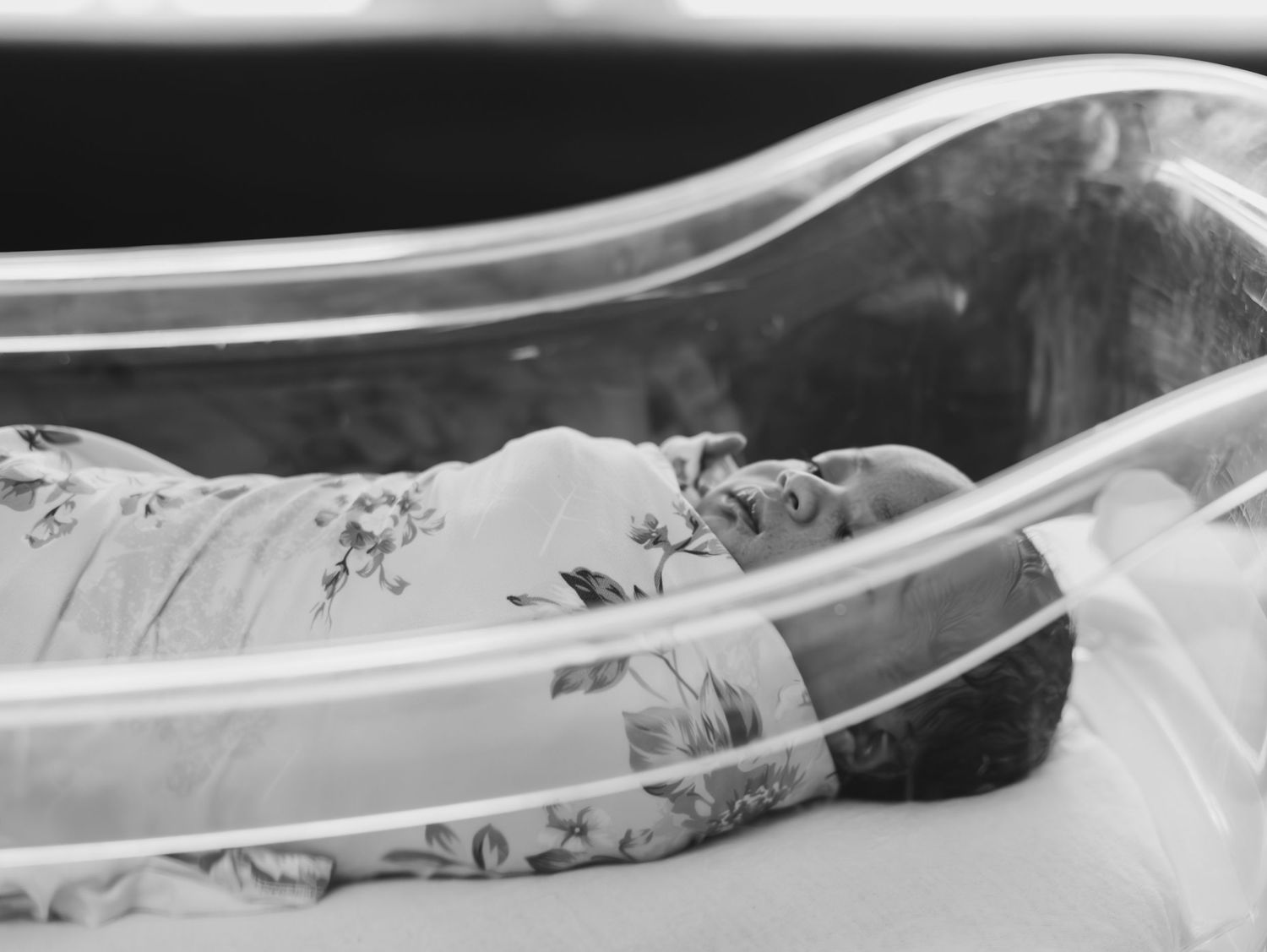 A black and white close-up photograph showing plastic tubing or medical piping with flowing curves against a dark background.