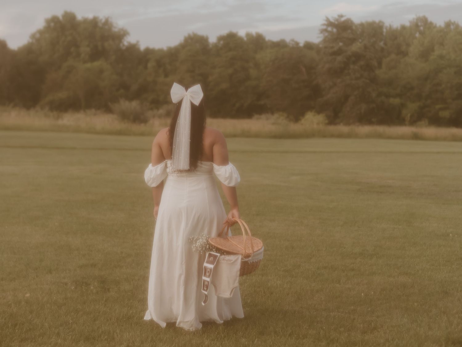 A couple in wedding attire walks hand in hand across a serene meadow in warm sepia tones.