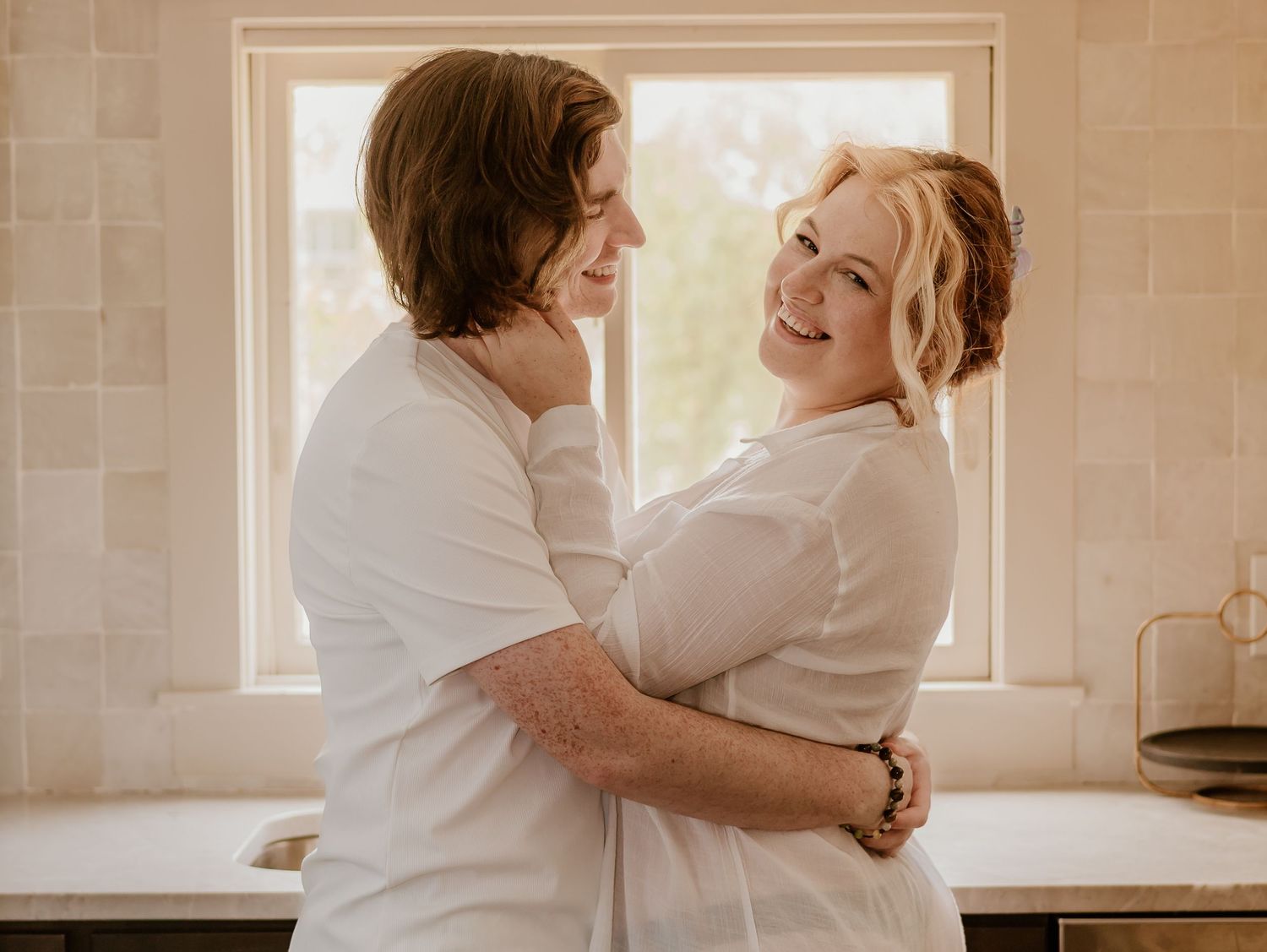 Warm-toned photo sequence of two people in white clothing hugging near a bright window.