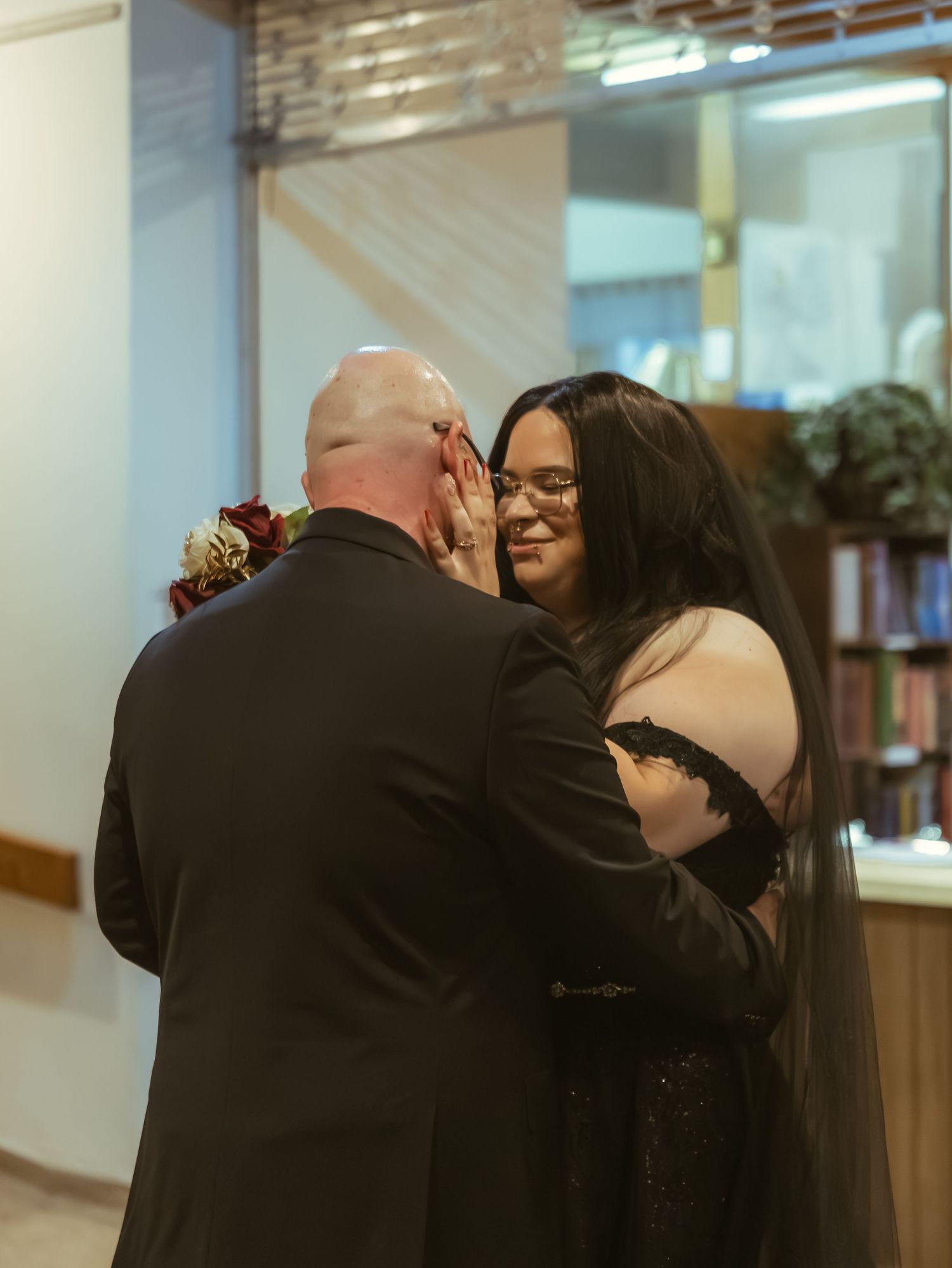 Emotional bride and groom share tender first look moment during gothic black wedding ceremony.