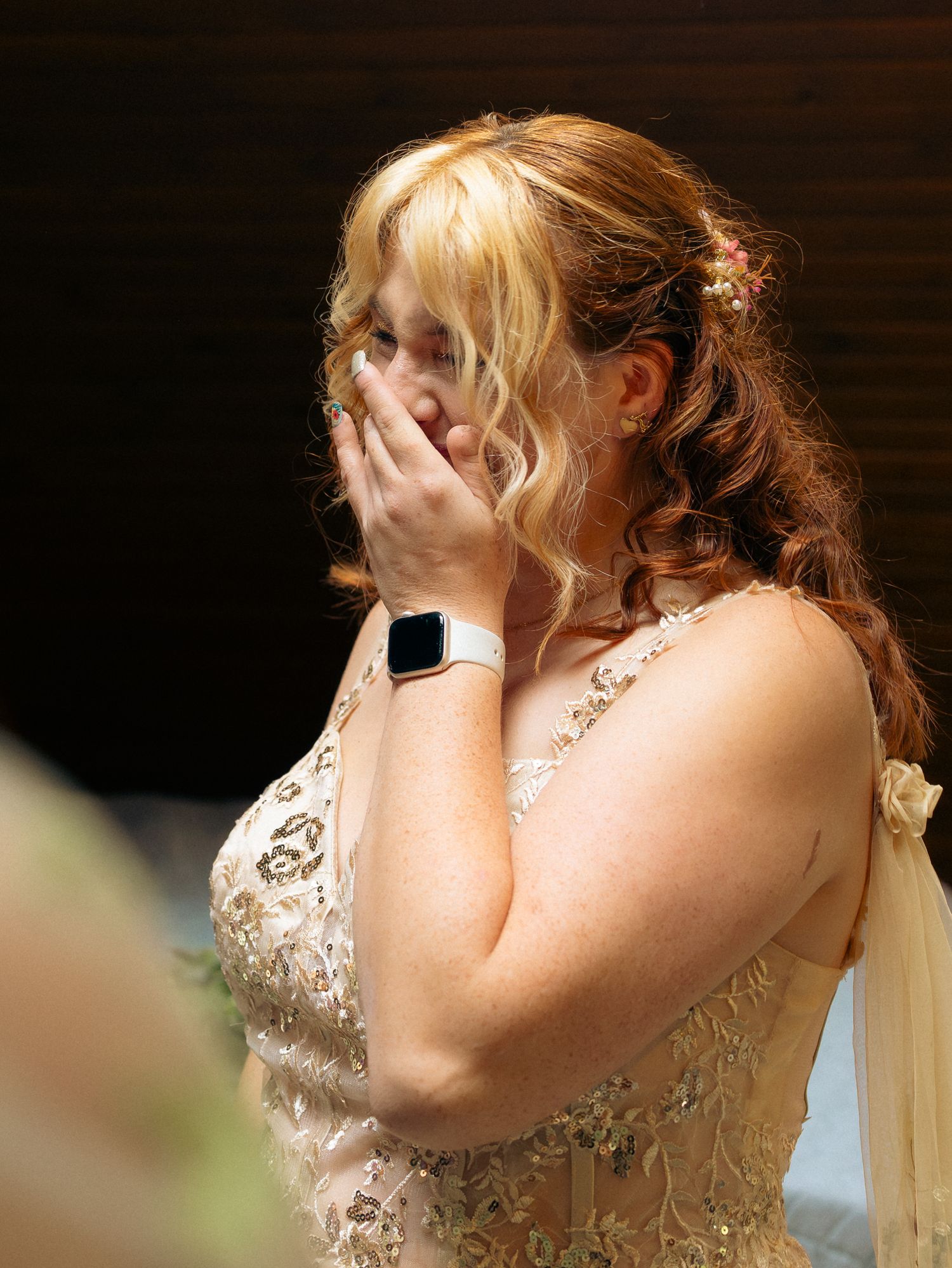 Emotional moment captured as someone in a white lace dress covers their face with their hands.