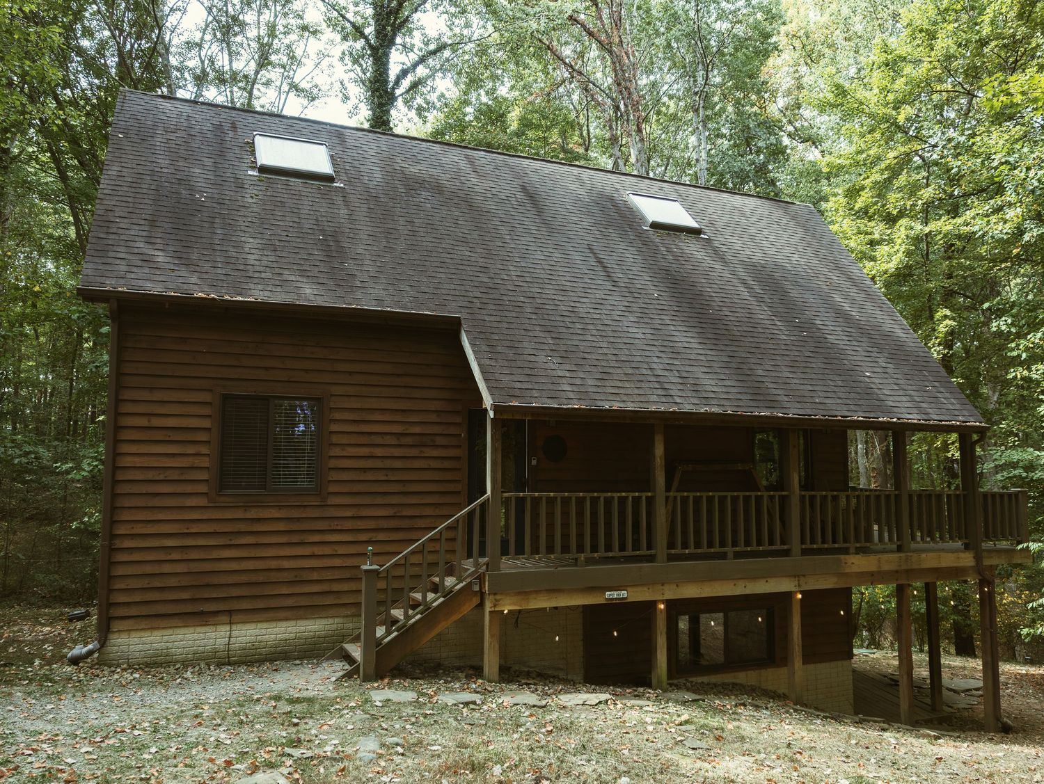 Row of rustic wooden cabins with porches nestled among green trees in a natural setting.