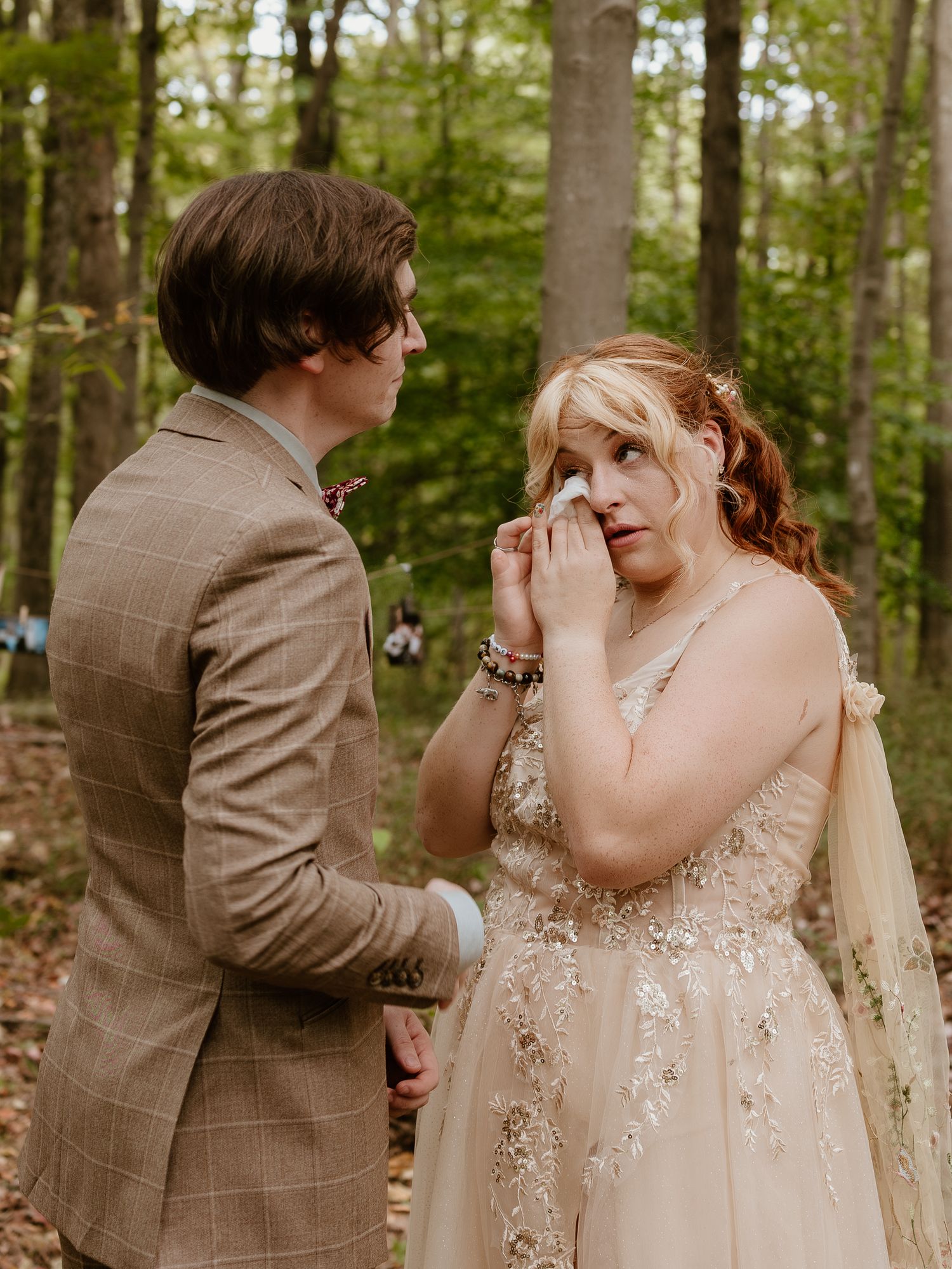 A romantic first look moment between a bride and groom in a sunlit forest setting.