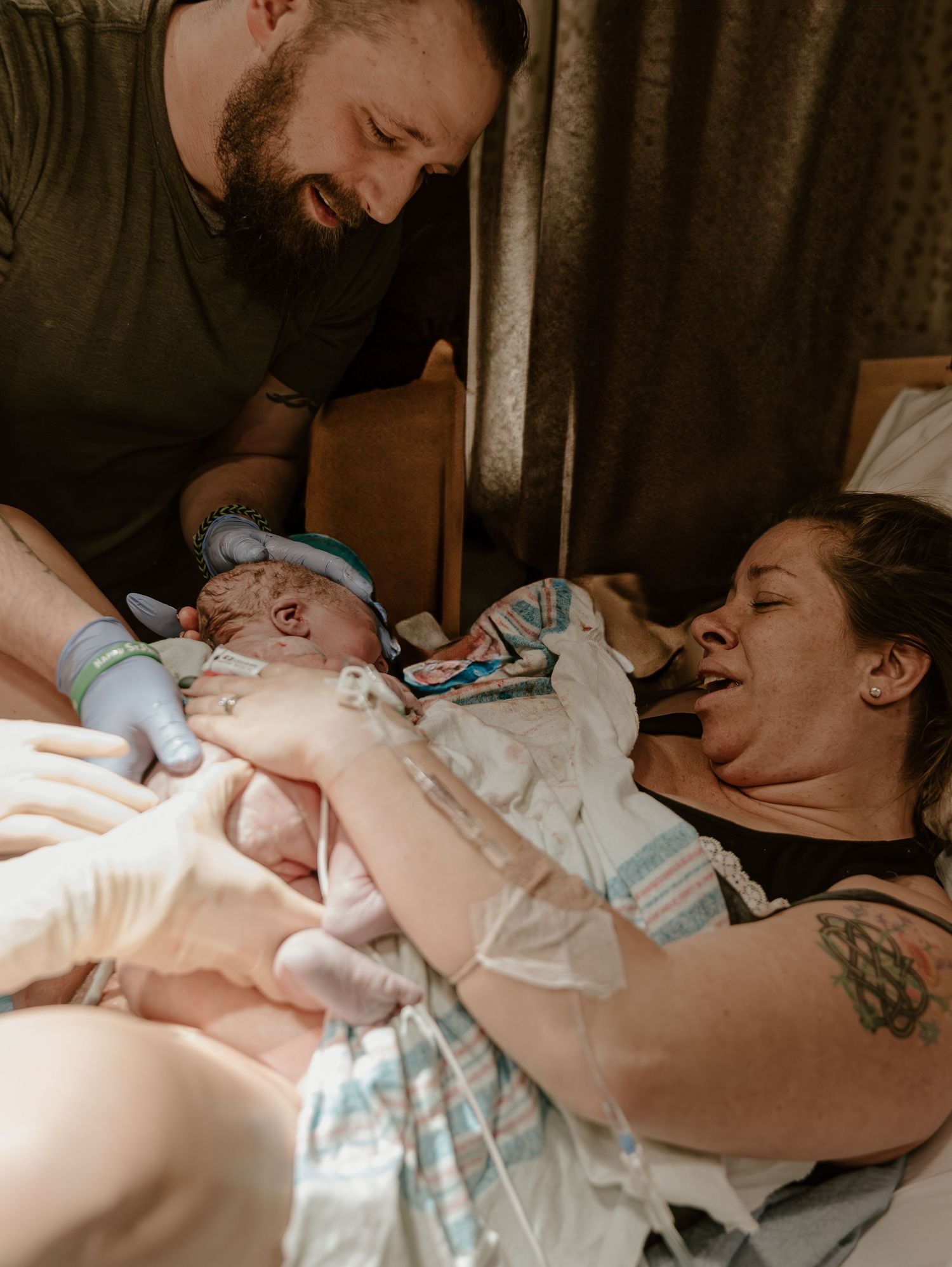 A newborn baby rests with parents in an emotional moment immediately after birth in the hospital.
