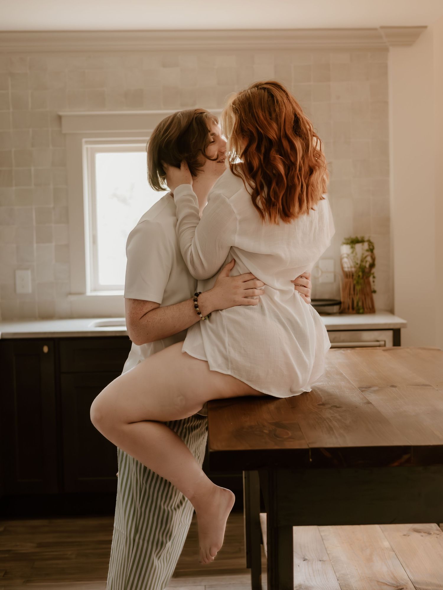 Intimate couple photography session in a minimalist kitchen with soft natural window light.