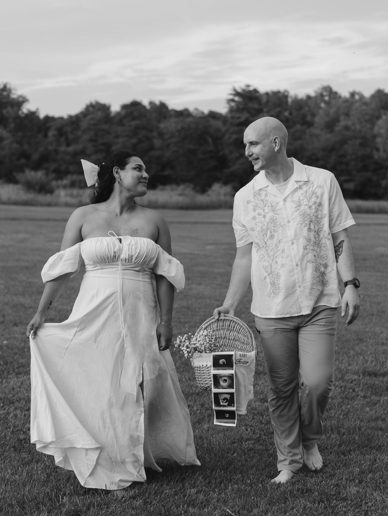 Black and white photo series of a couple in a field sharing ultrasound photos and celebrating a pregnancy announcement.