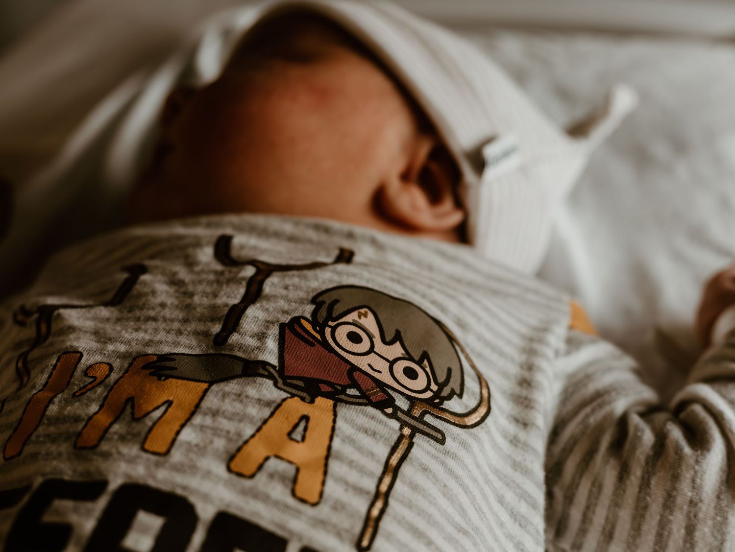 A sleeping person lies in bed with a graphic t-shirt and patterned bedding visible.
