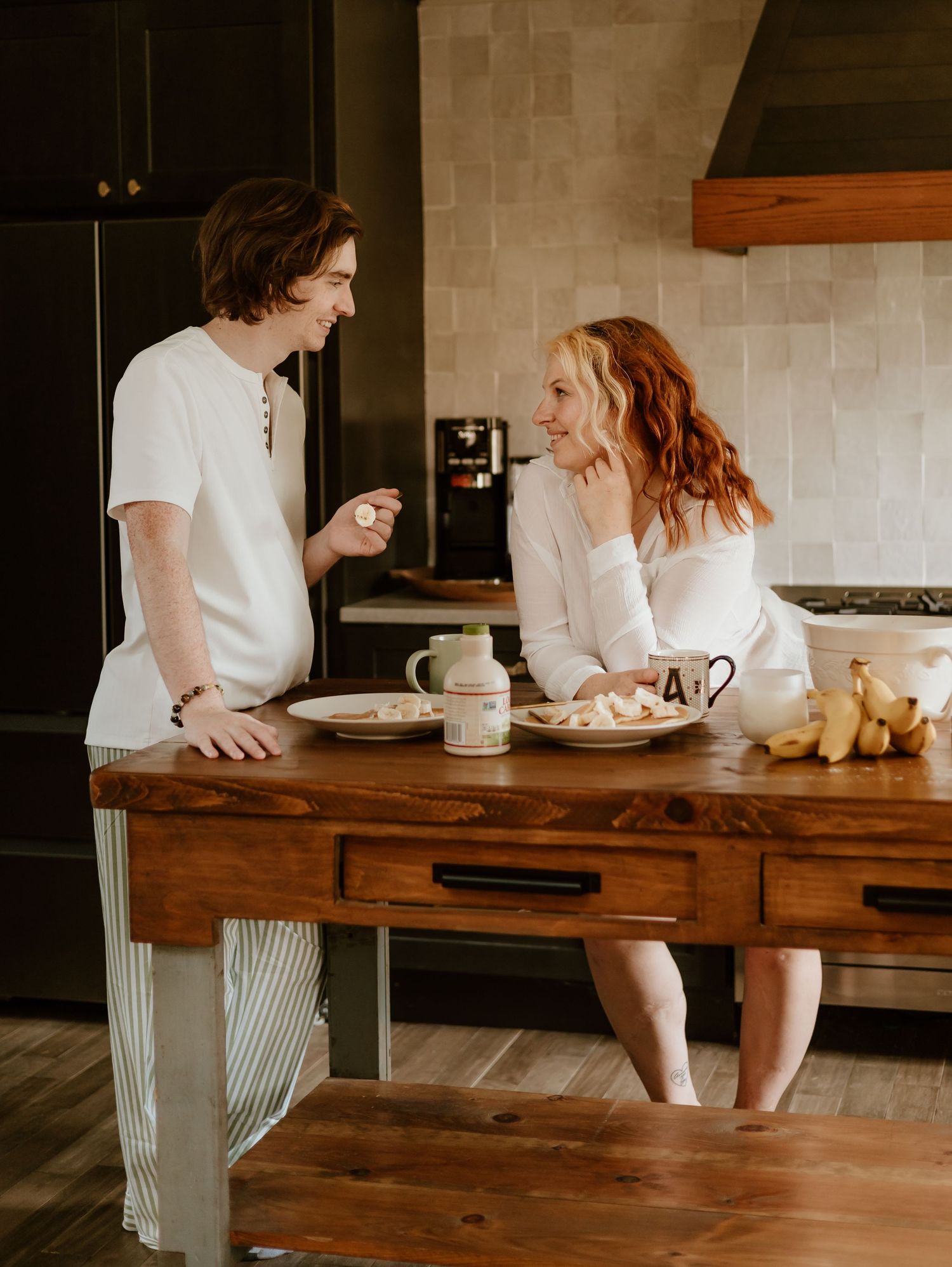 Couple sitting at rustic wooden table sharing intimate conversation over coffee and breakfast.