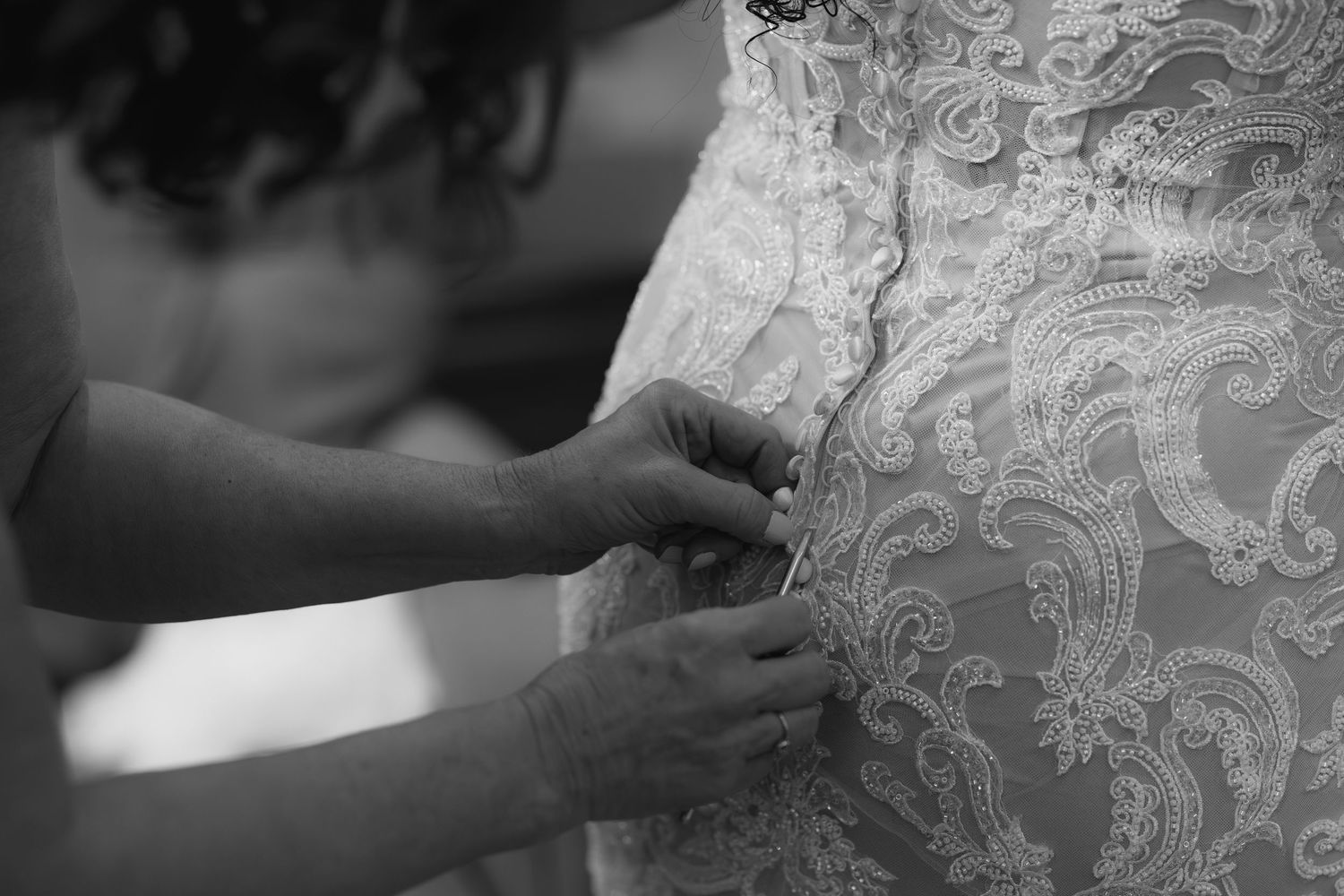Close-up detail of intricate white lace and beading on a wedding dress.