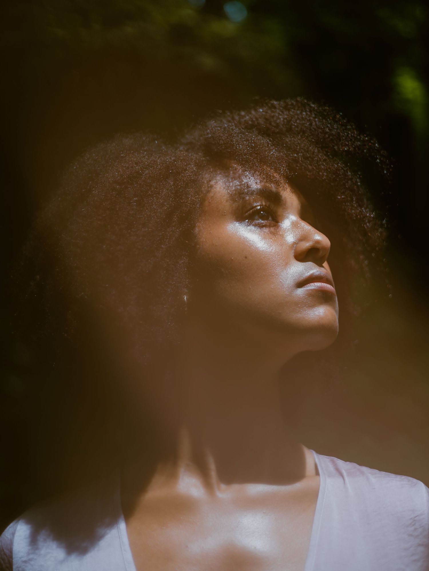 Artistic portrait in natural lighting with dramatic shadows casting across neutral background.