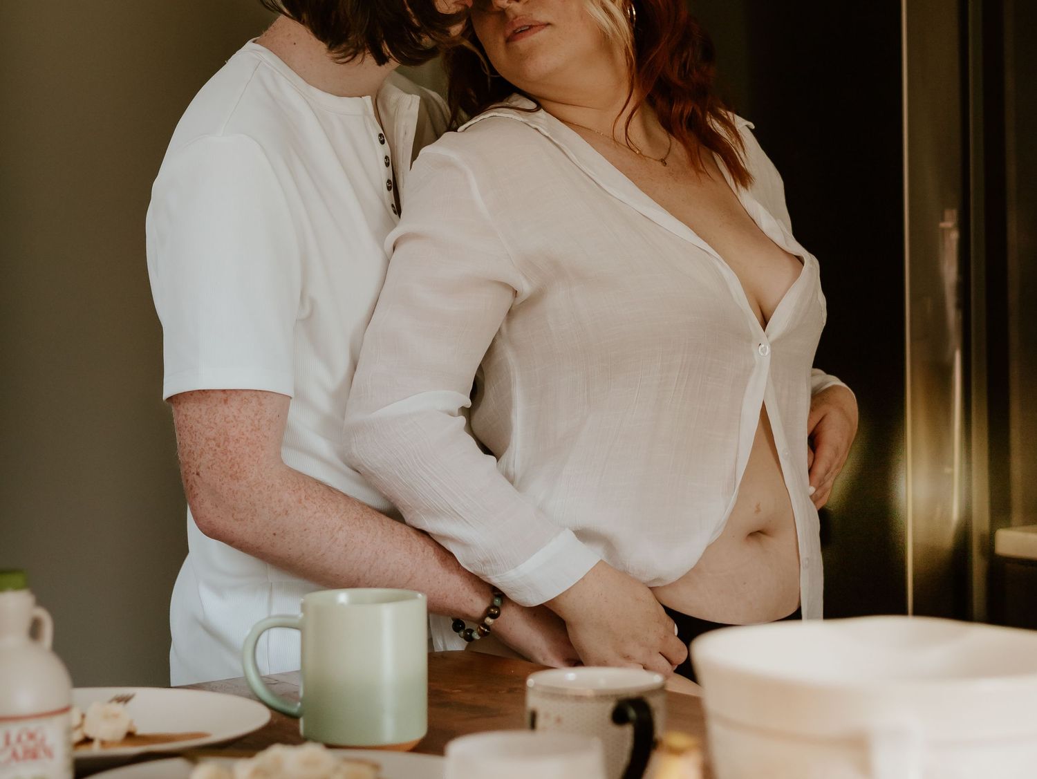 Coffee cups and hands on a wooden table in a cozy morning setting.