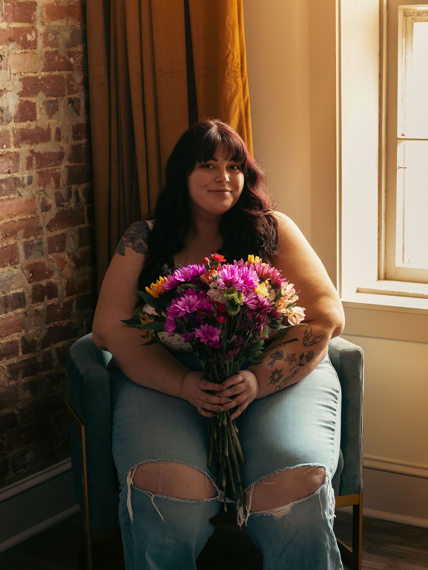 Two legs with a bouquet of pink and white flowers against a brick wall and sunlit window.