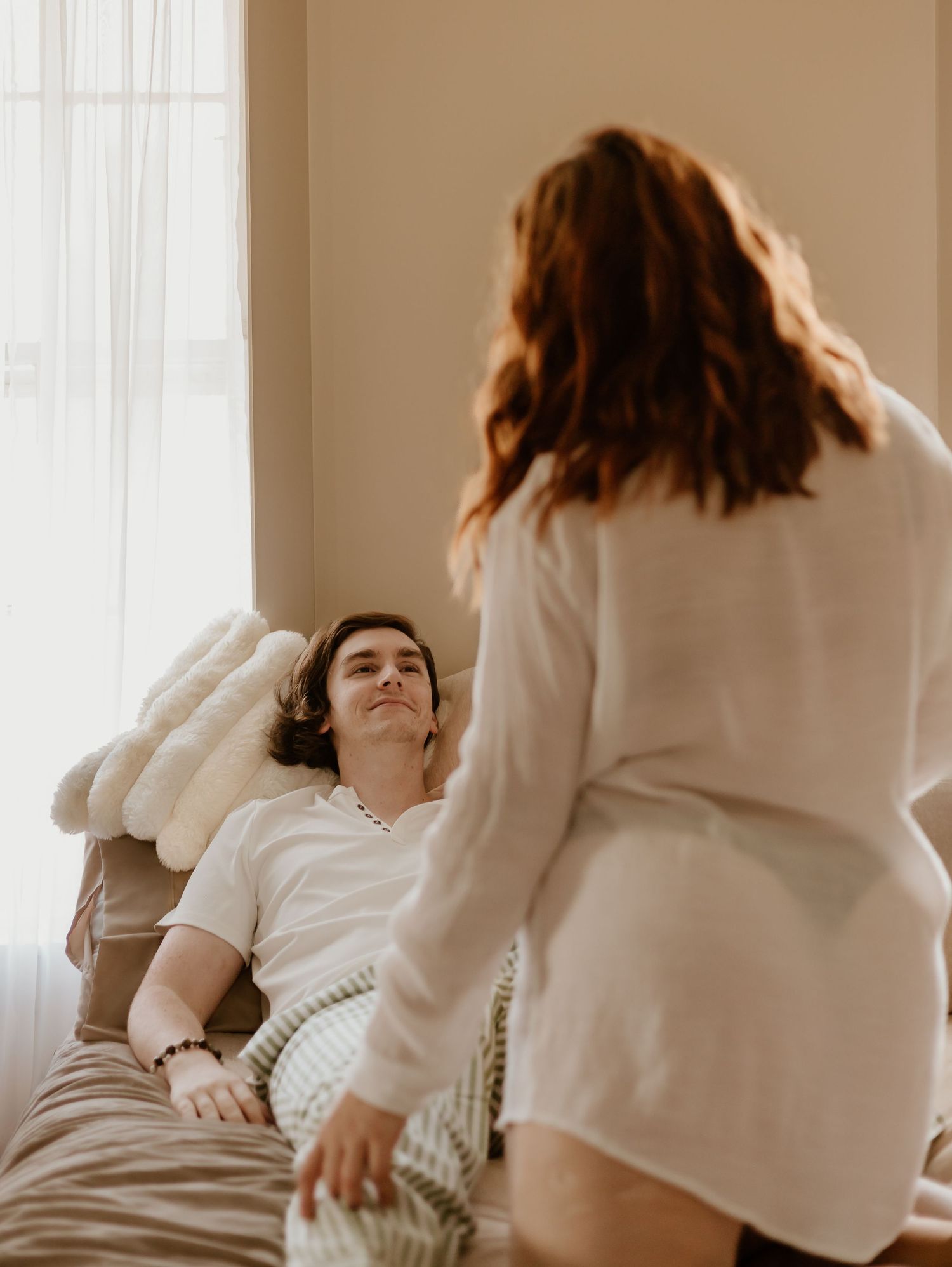 Intimate portrait series in warm tones showing tender moments between couple on light-filled bed.