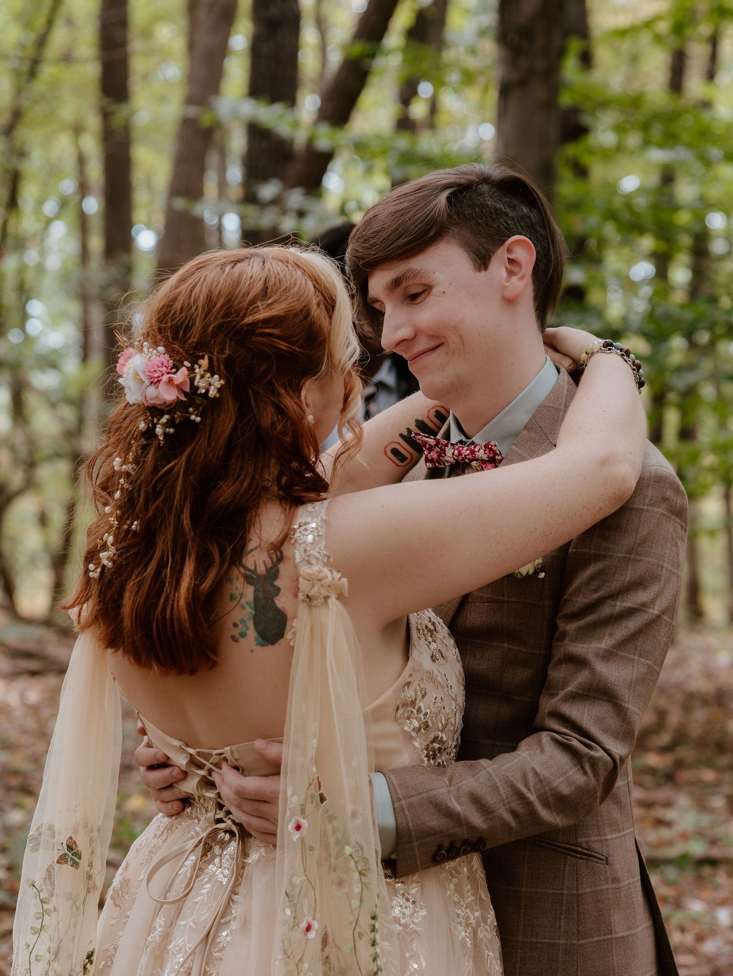 A romantic woodland wedding photoshoot showing tender moments between a couple among trees and flowers.