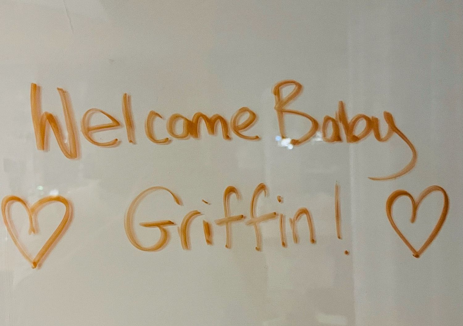 A welcome message written in orange on a white surface with hearts.