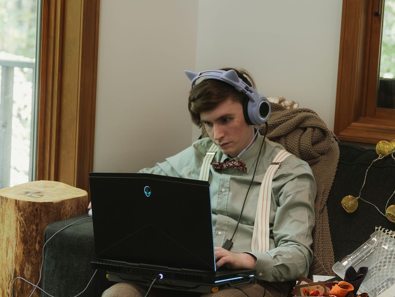 A person wearing headphones works at a desk with a computer monitor in a wood-paneled room.