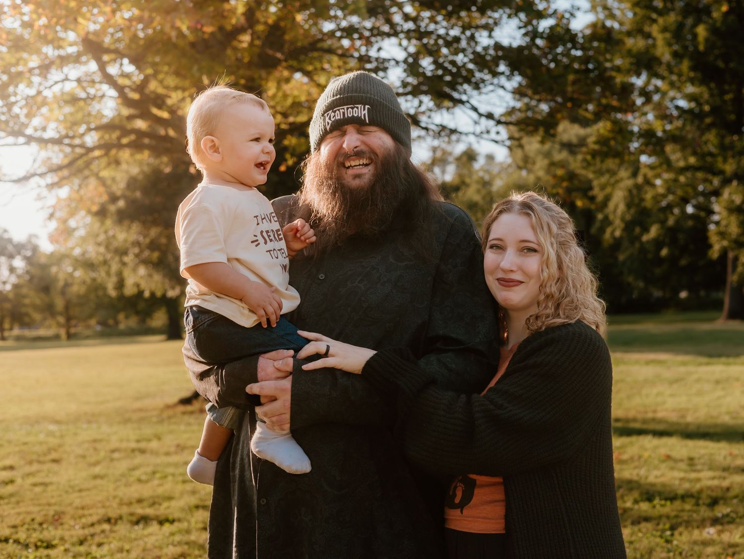 Family sharing warm embraces in a park during golden hour sunlight.