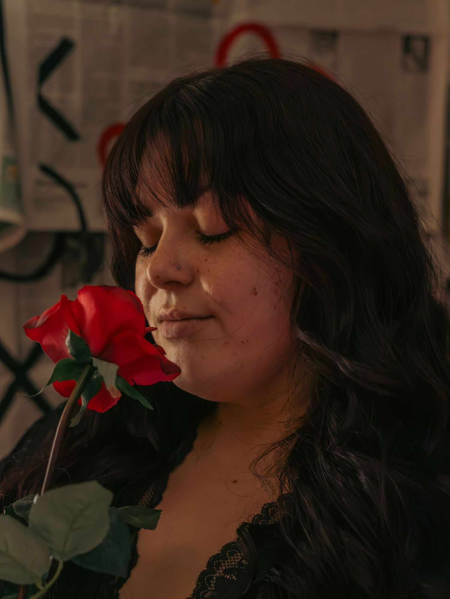 A serene moment smelling a red rose against a dark background.