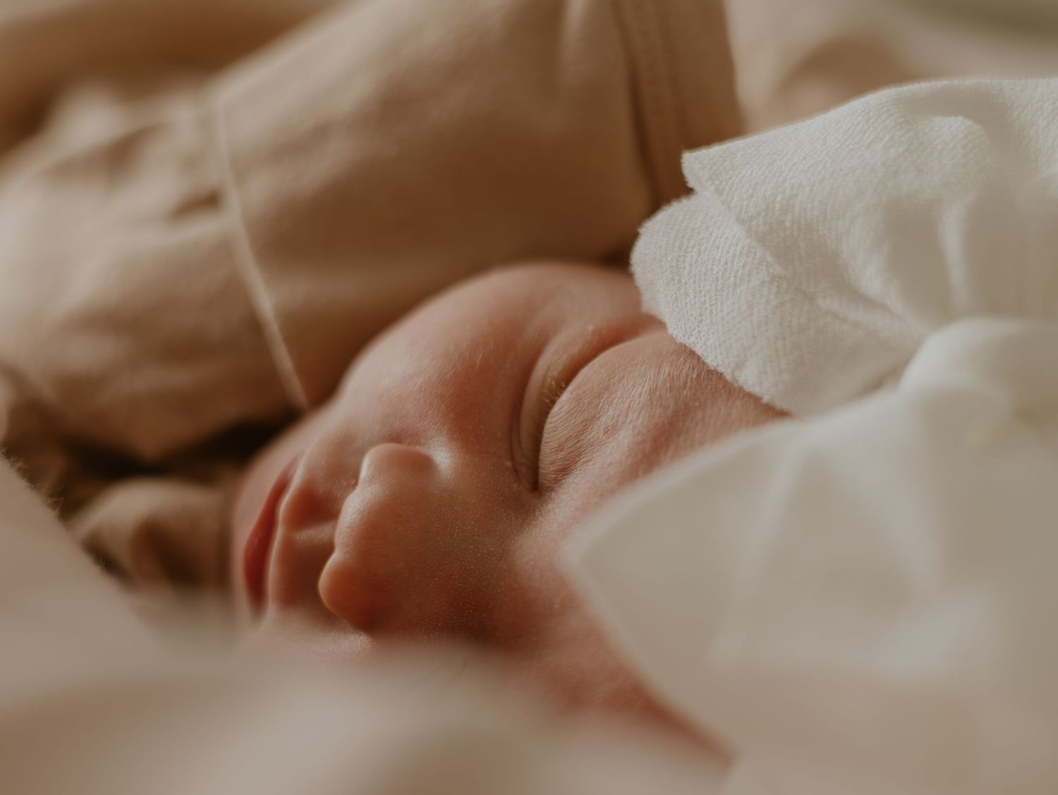 A close-up view of soft white sheets or bedding showing gentle folds and creases.