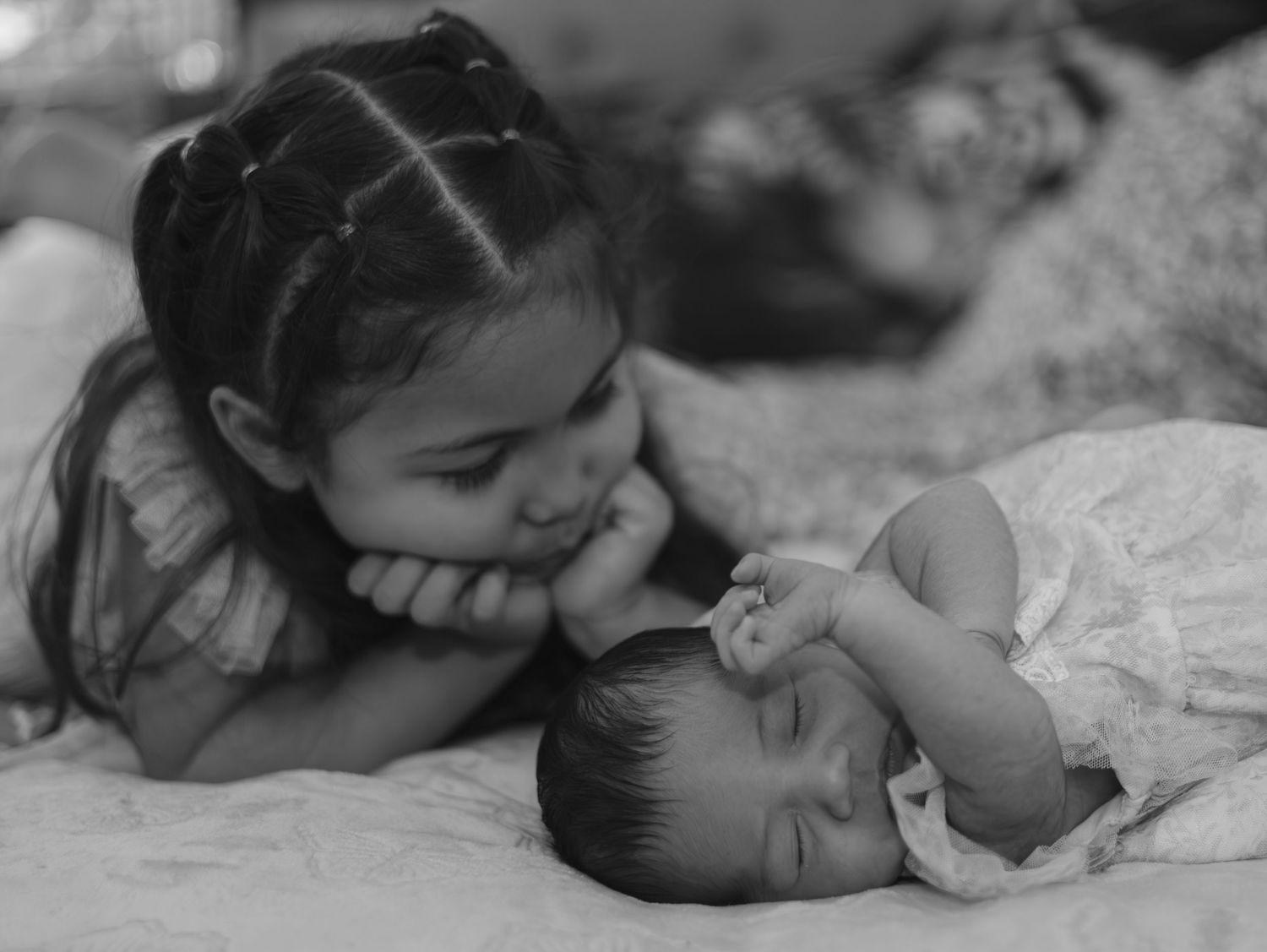 A black and white photo series showing a sleeping baby in different peaceful poses on white fabric.
