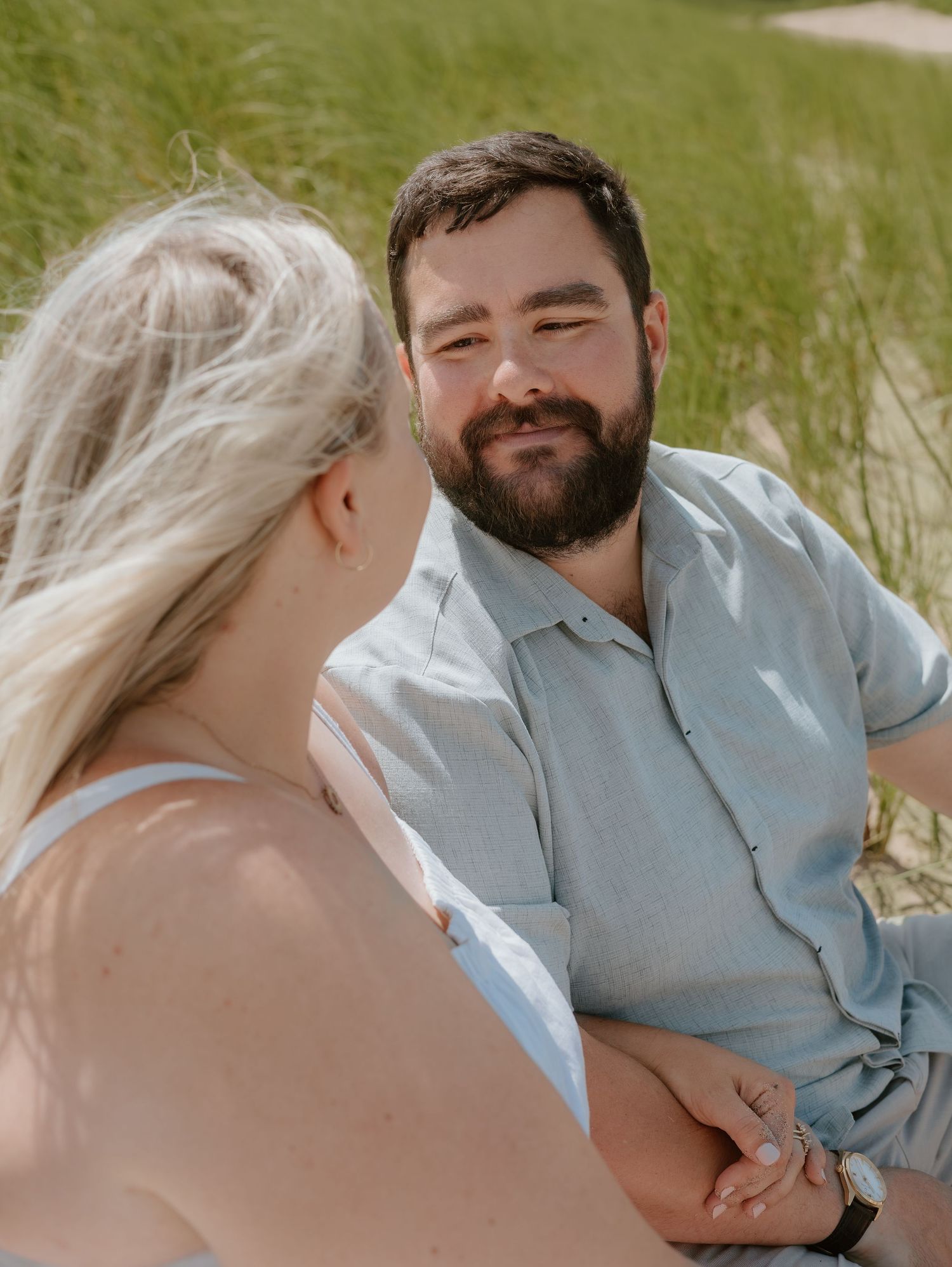 Couple sharing tender moments together in a grassy outdoor setting with warm sunlight.