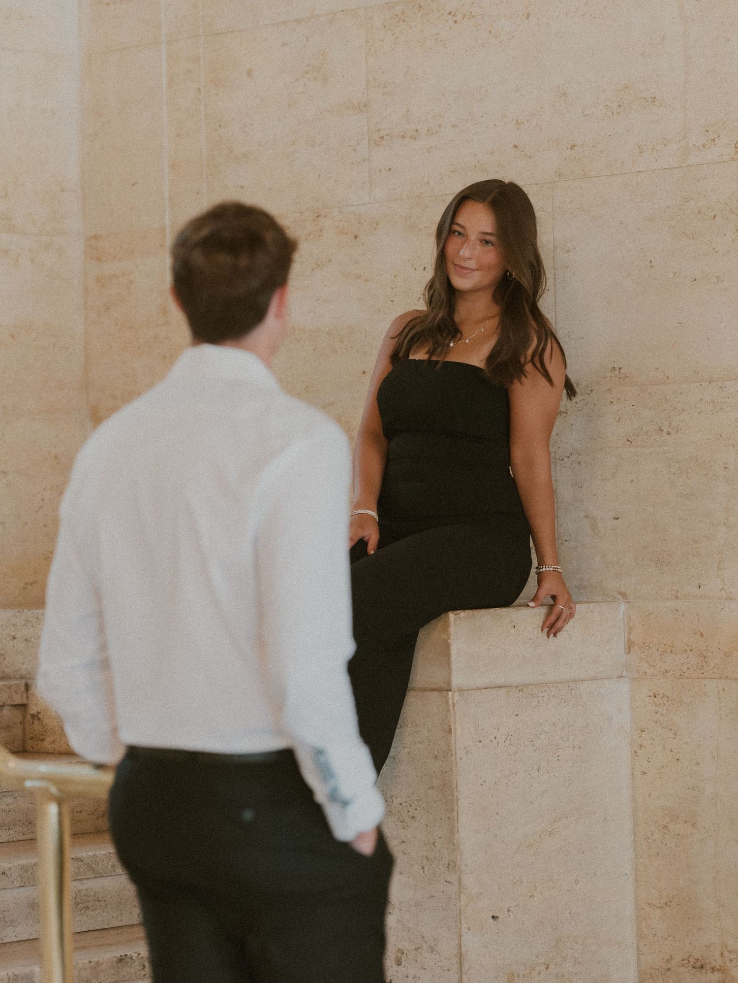 A couple in formal attire, with one person in black and one in white, dancing together in an elegant setting.