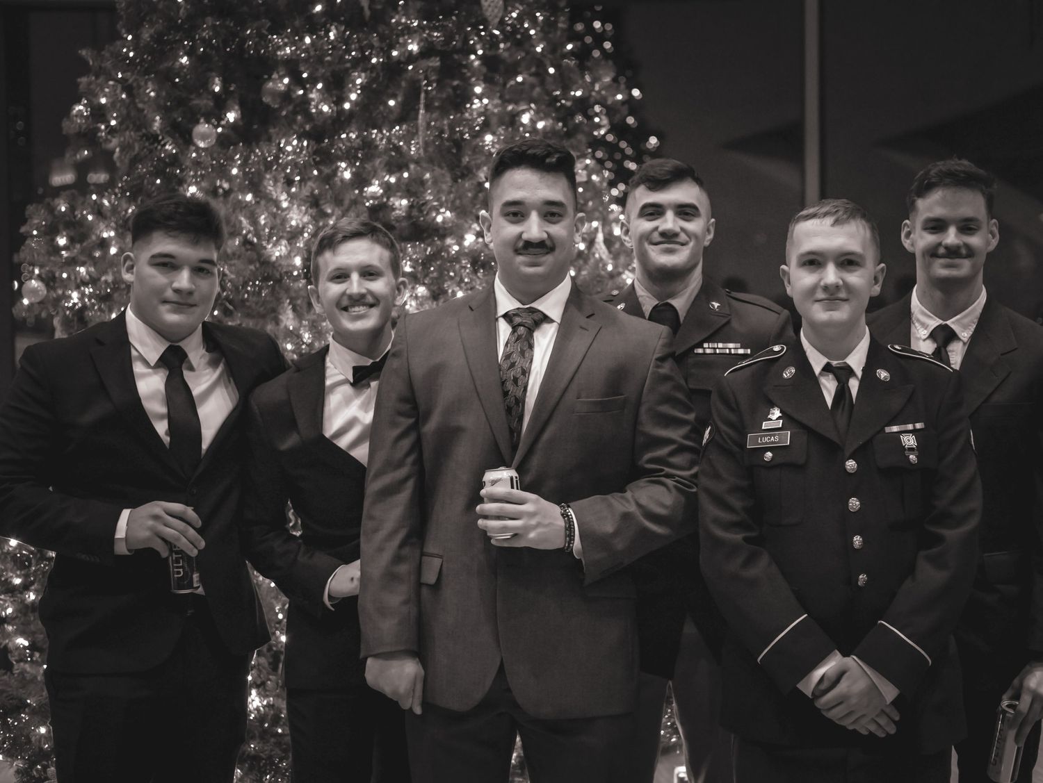 Military and civilian guests posing in front of a Christmas tree at a formal gathering.
