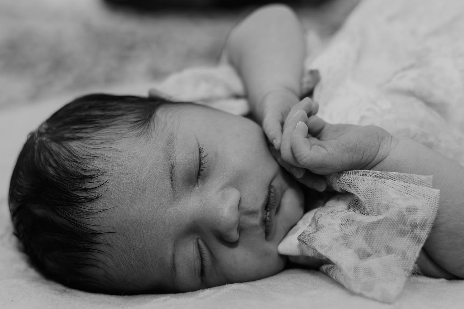 Close-up view of a sleeping infant swaddled in white fabric.