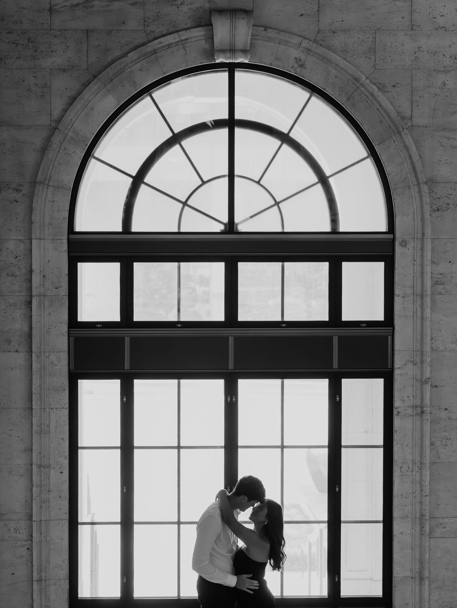 Dramatic silhouettes against large arched windows in an architectural setting.
