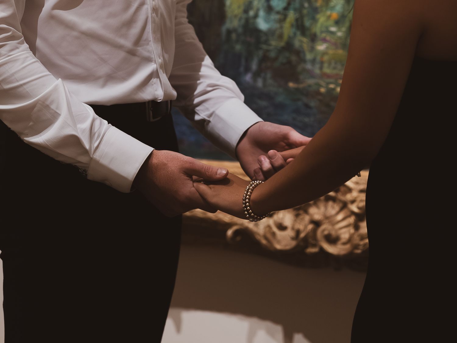 Close-up view of hands exchanging wedding rings during an intimate ceremony.