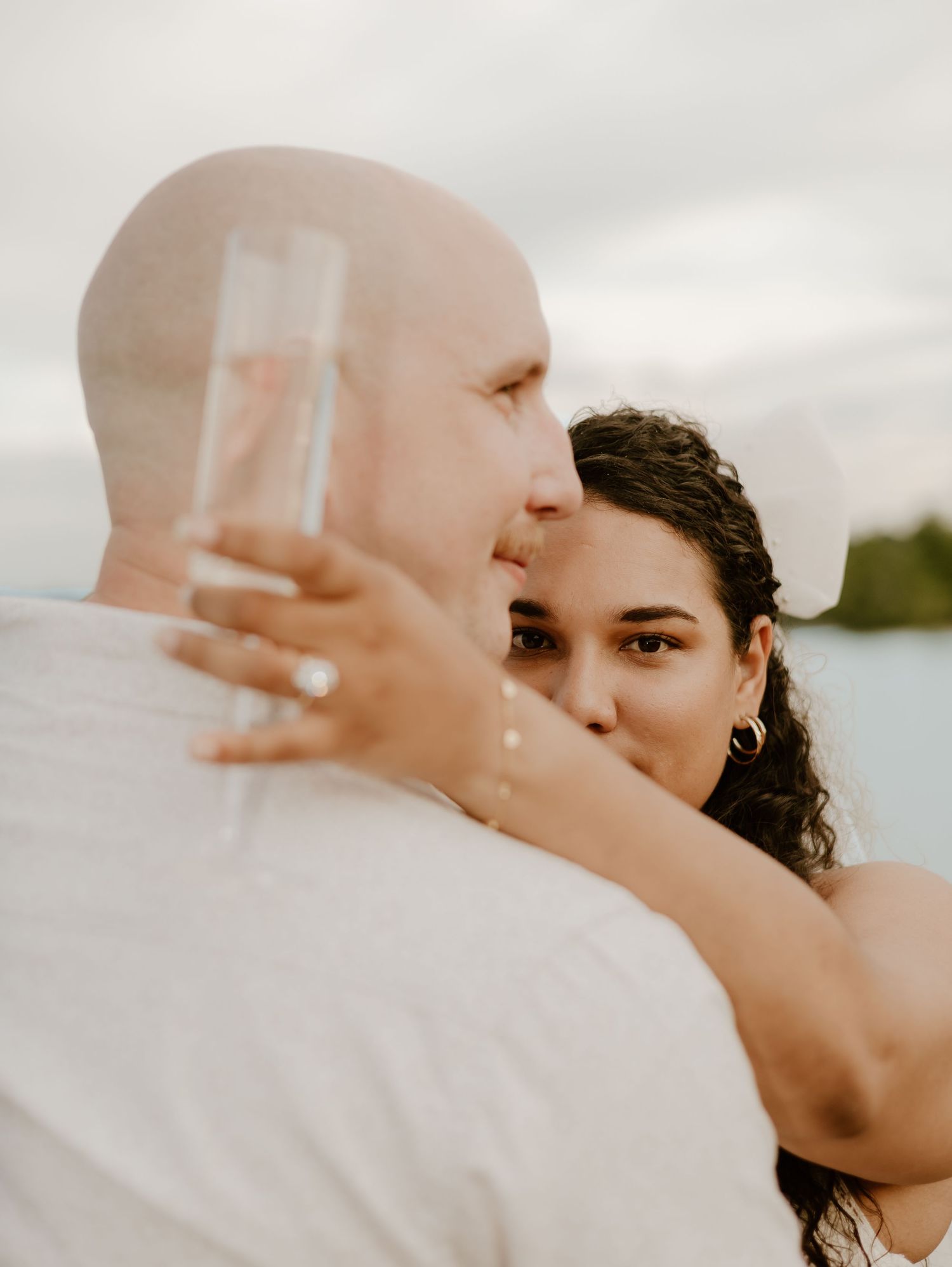 Close-up wedding portrait shows tender embrace between newlyweds with soft natural lighting and blurred background.