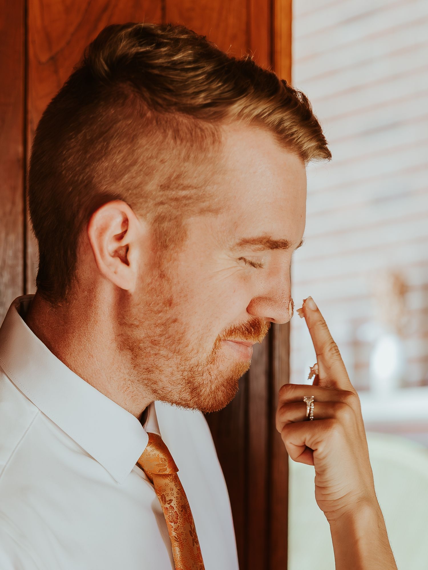 A groom in a white dress shirt and brown tie adjusts his collar in a series of candid getting-ready photos.